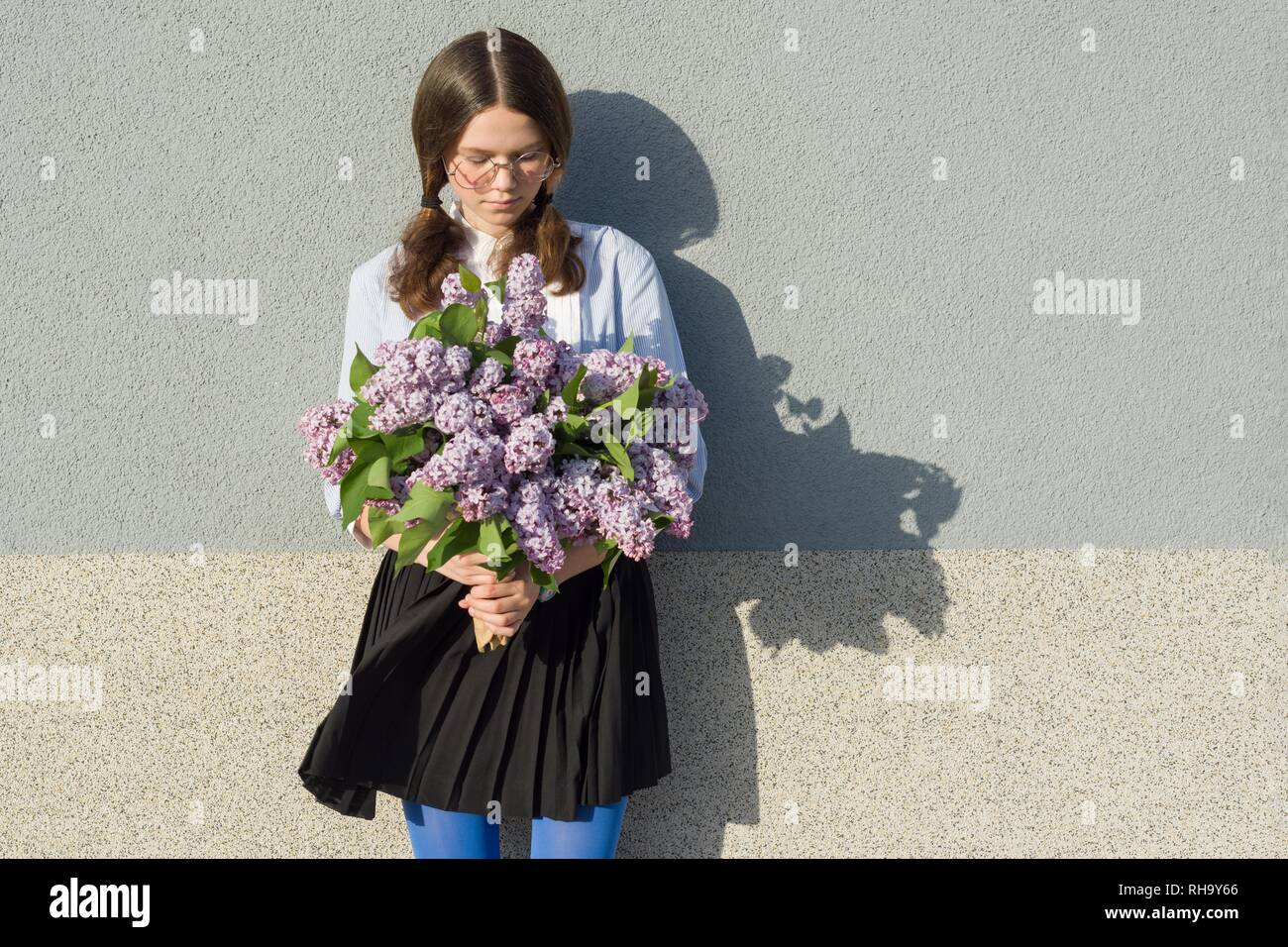 Portrait romantic teenage girl with bouquet of lilacs on gray wall ...