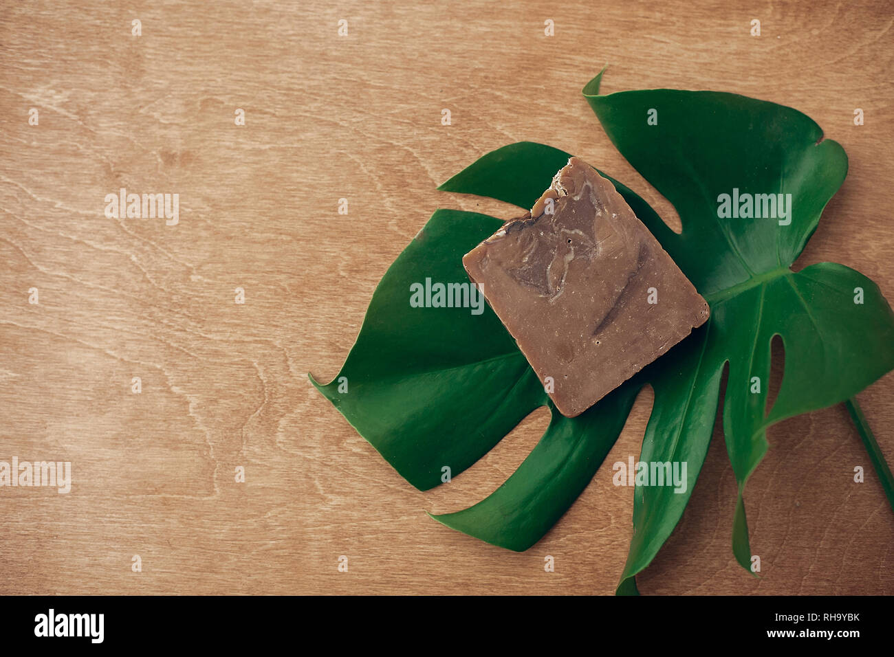Natural soap on wooden background with green monstera leaf. Plastic free beauty essentials. Zero waste concept, flat lay with copy space. Sustainable  Stock Photo