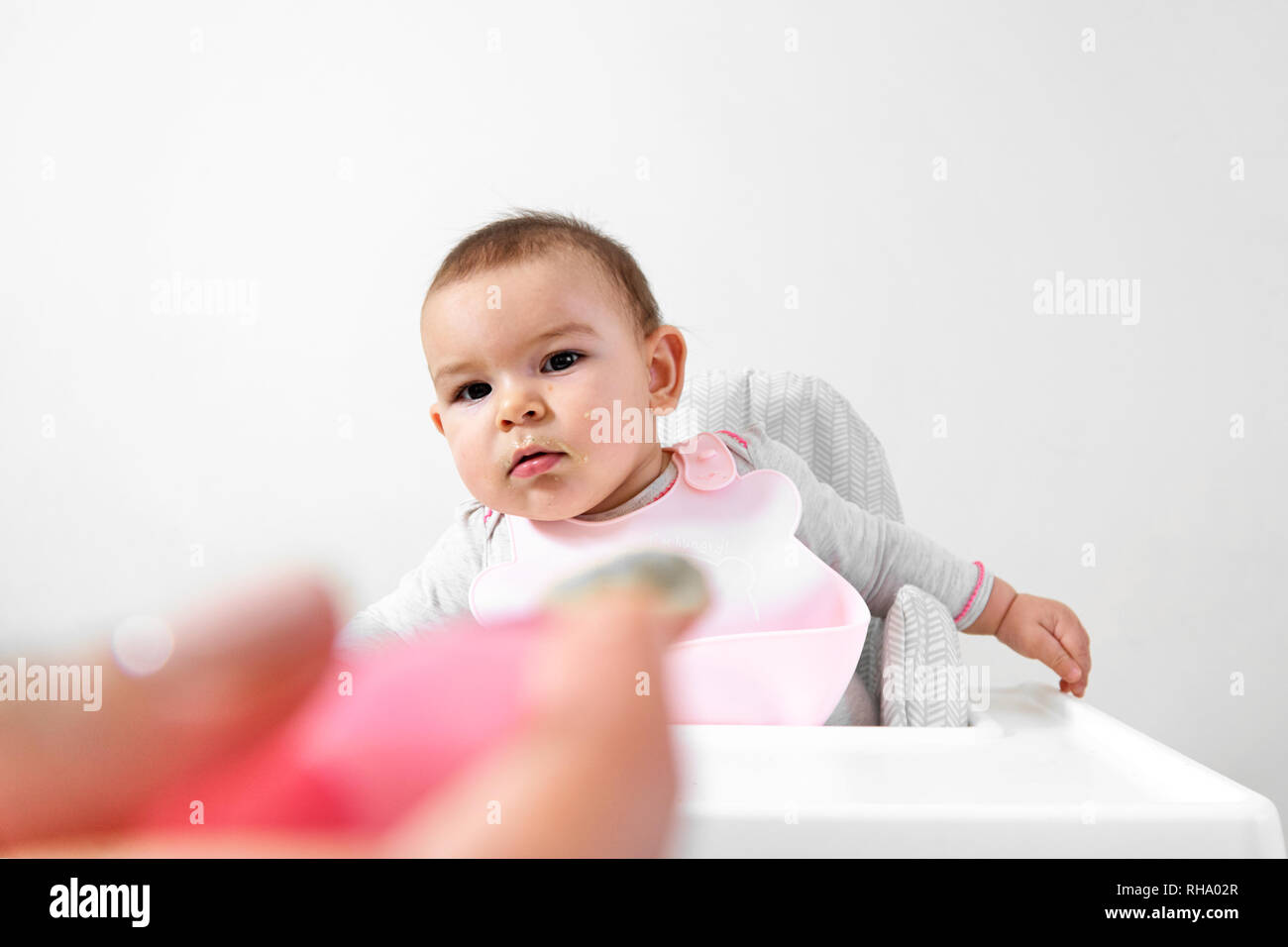 Happy baby toddler in high chair with spoon in his hand Stock Photo Alamy