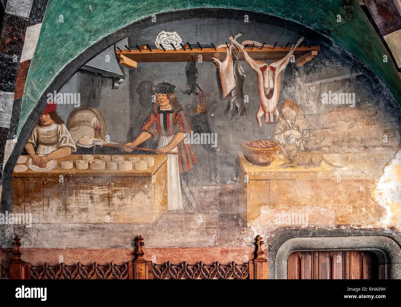 Italy Valle d'Aosta Issogne the Castle - courtyard - frescoed arcade -The baker fires the freshly kneaded bread and the baker spins the spit while a cat tries to steal the meat Stock Photo