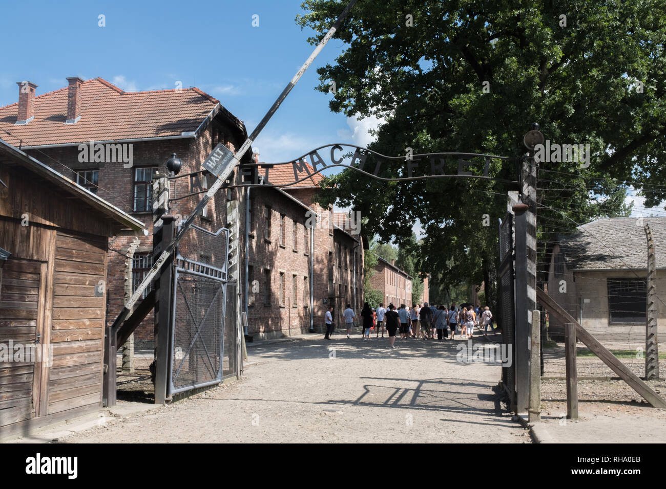 Entrance gate Albeit Macht Frei at Auschwitz with tour group in the background Stock Photo