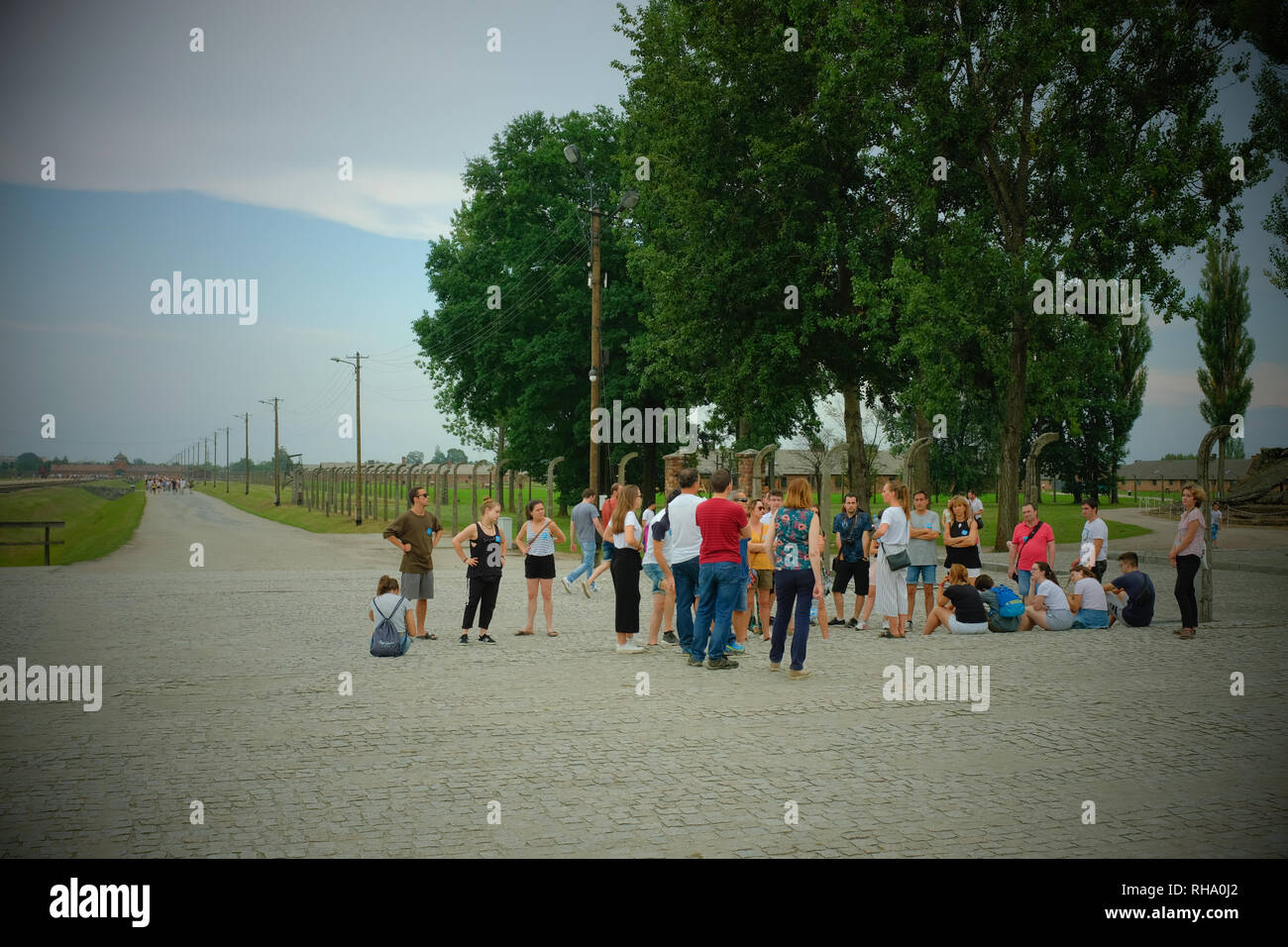 tourists outside at Birkenau Auschwitz listening to a tour guide Stock Photo