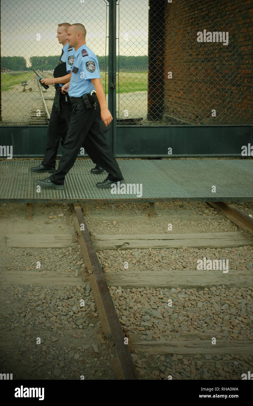 two policemen patrolling Auschwitz walking across rail track Stock Photo