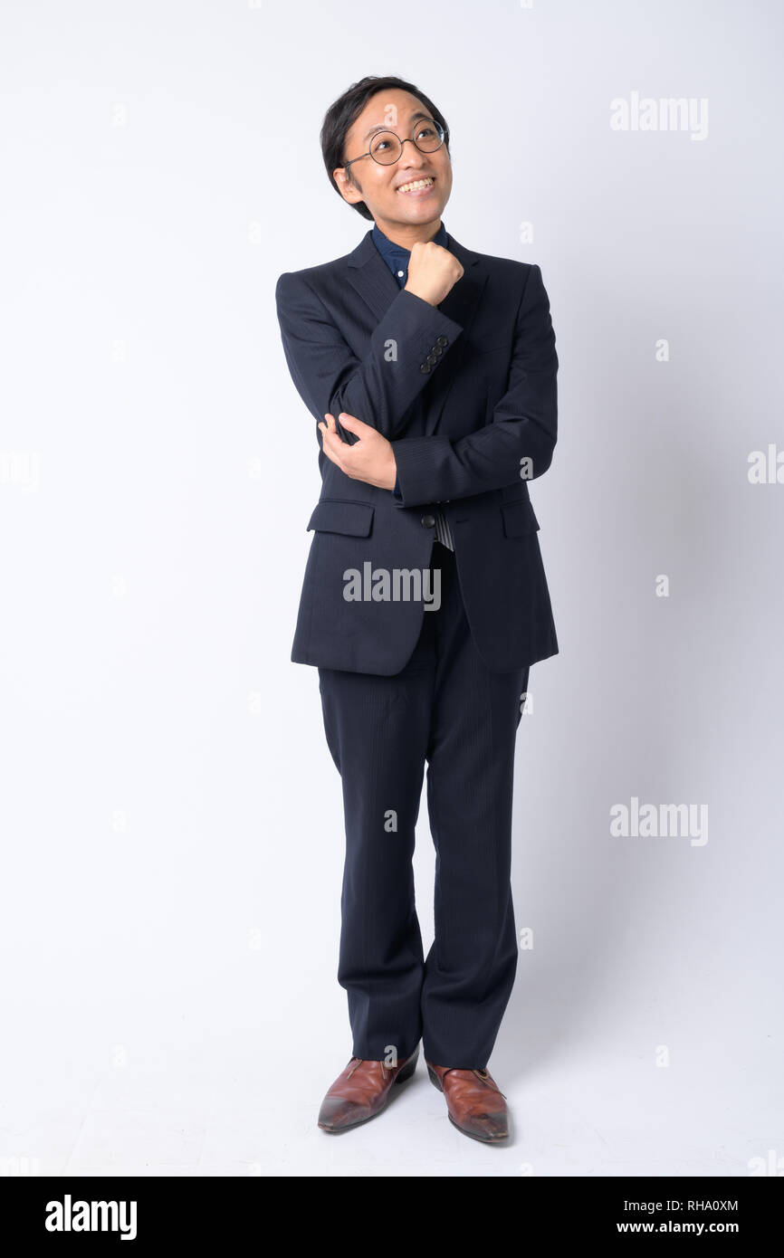 Full body shot of happy Japanese businessman in suit thinking Stock ...