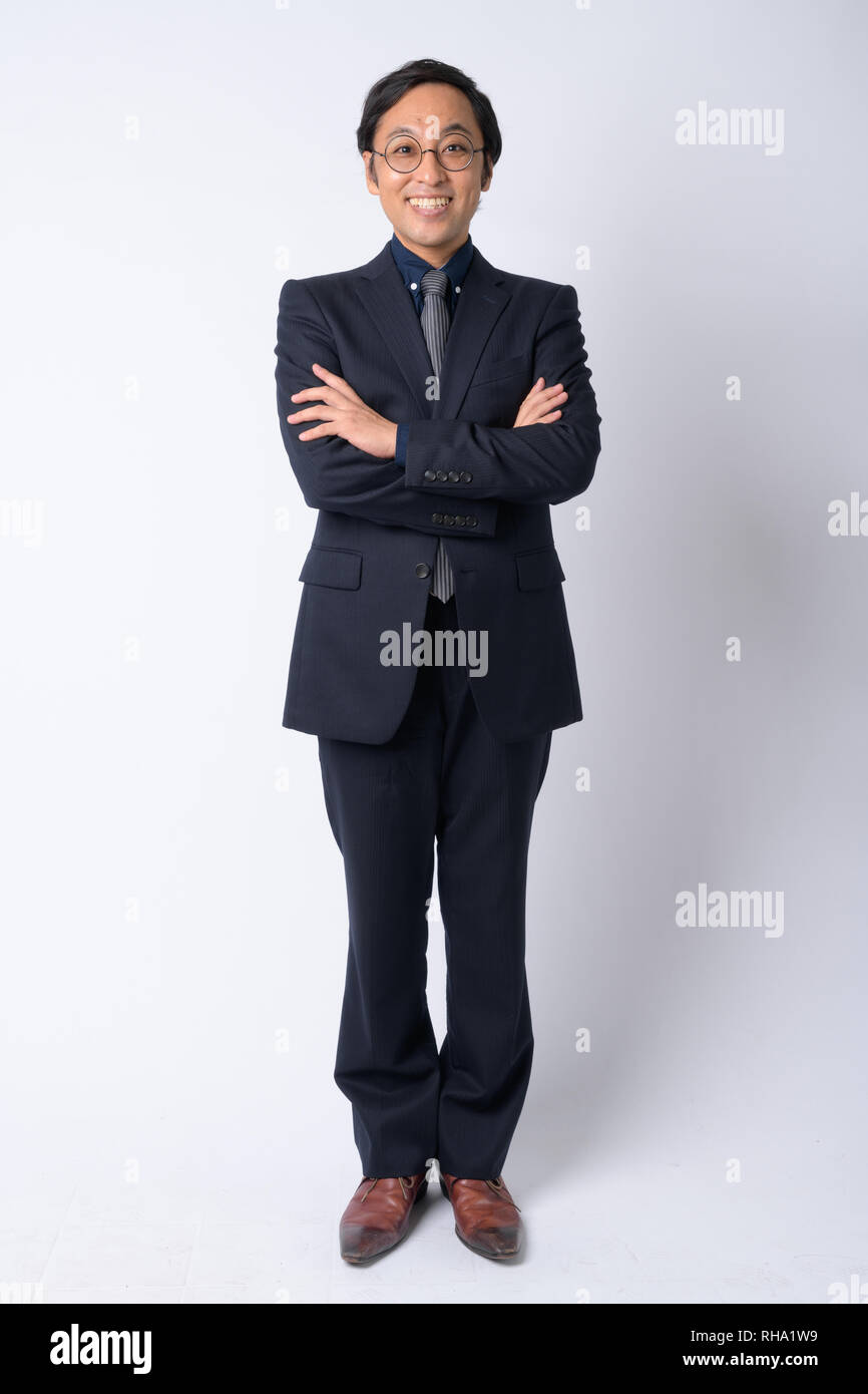 Full body shot of happy Japanese businessman in suit with arms crossed ...