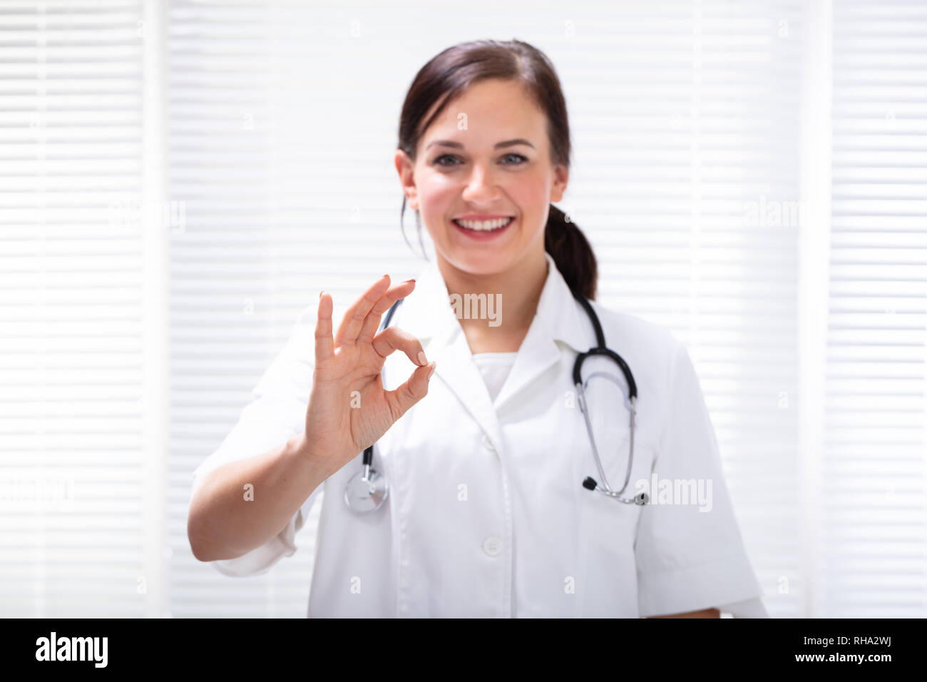 Happy Female Doctor Gesturing Ok Sign In Clinic Stock Photo