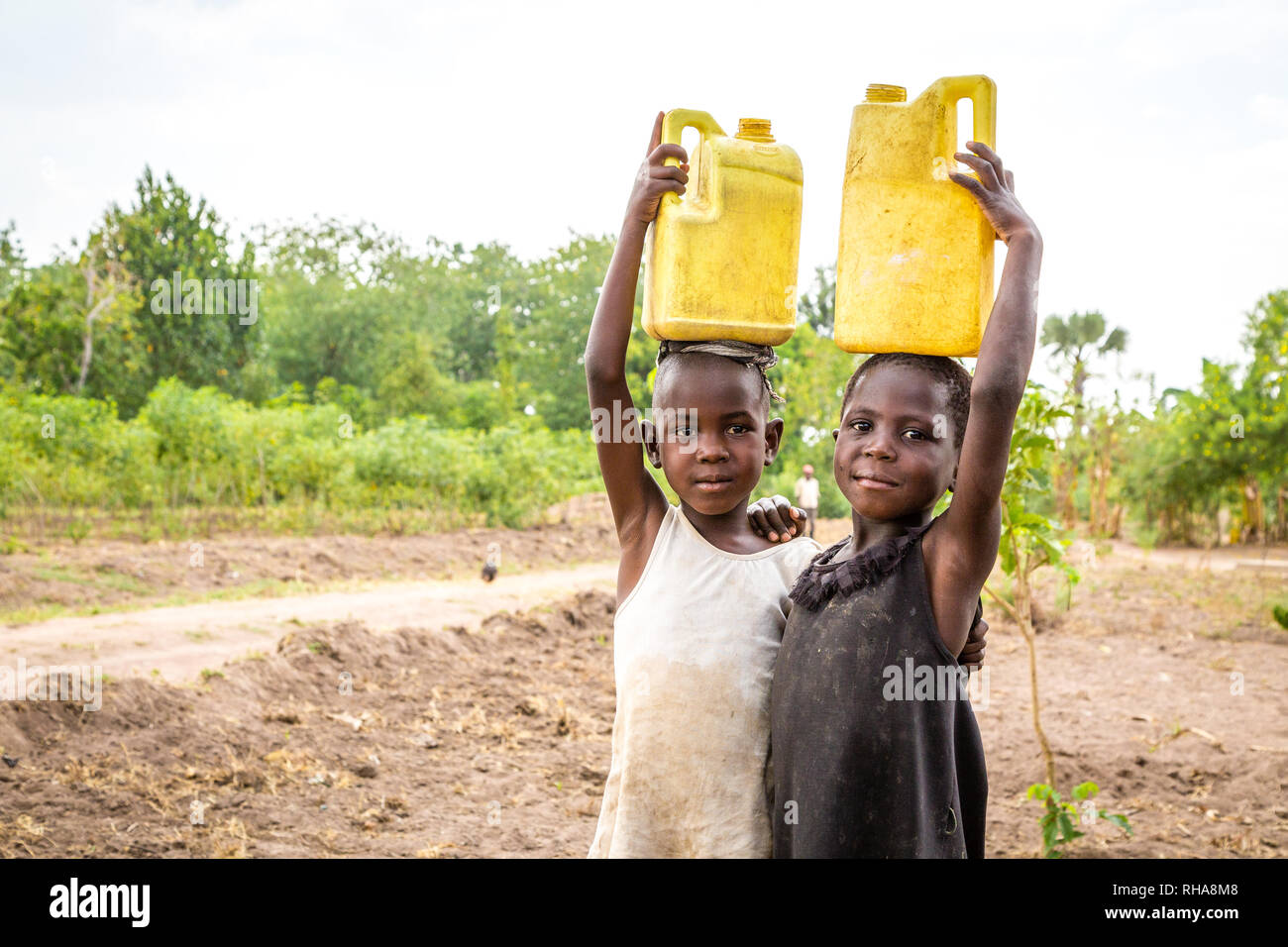 Portrait of two village girls carrying petrol cans with water, Tororo District, Uganda Stock Photo