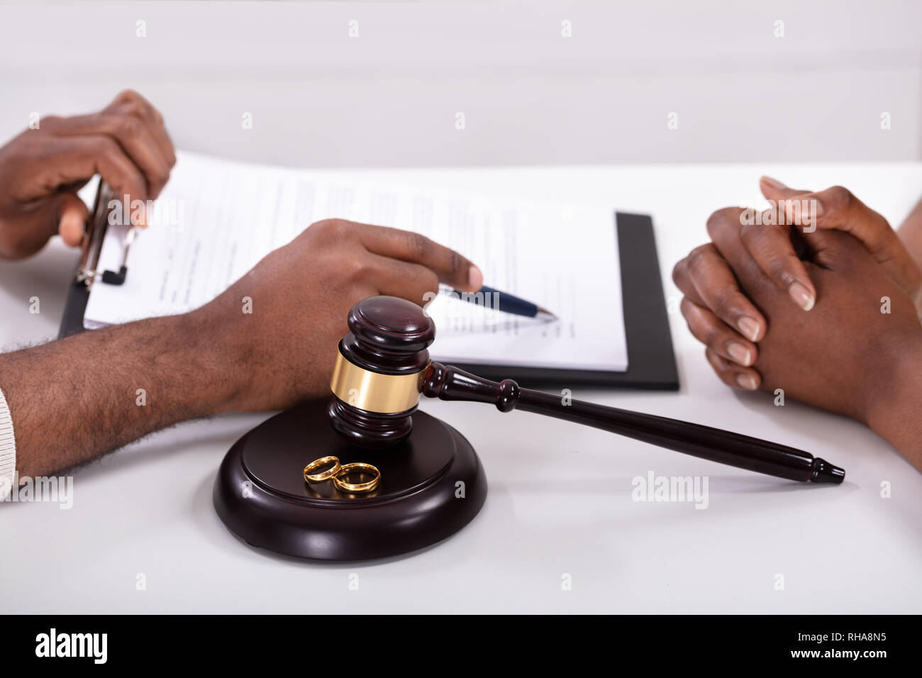 Close-up Of A Judge Explaining Contract To His Client With Gavel And Golden Rings Stock Photo