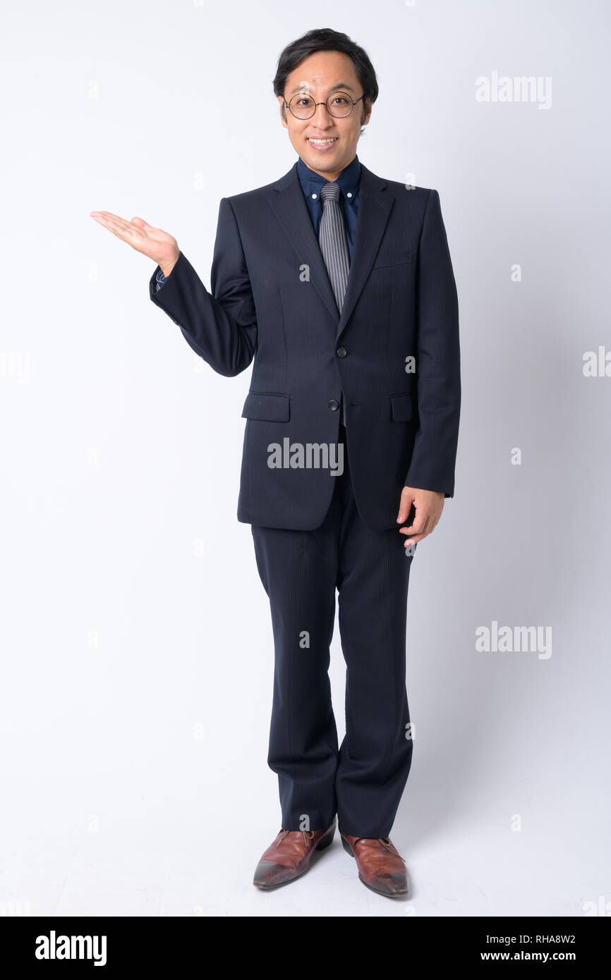 Full body shot of happy Japanese businessman in suit showing something ...