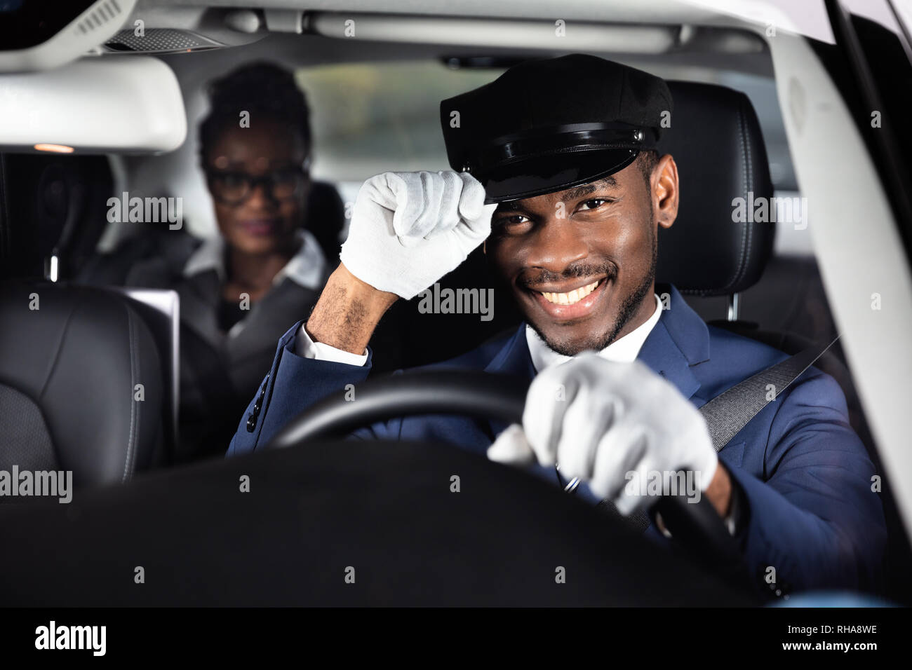 Portrait Of A Smiling Male Chauffeur Driving Car With Businesswoman In