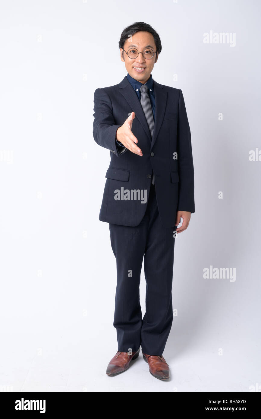 Full body shot of happy Japanese businessman in suit giving handshake ...