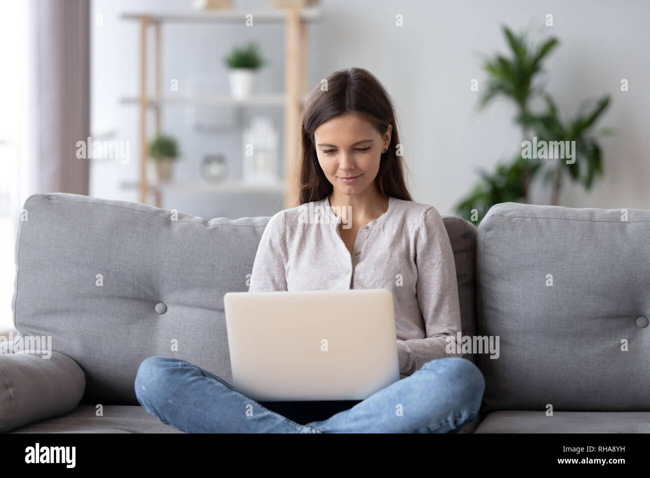 Happy teen girl using laptop surfing web sitting on couch Stock Photo ...