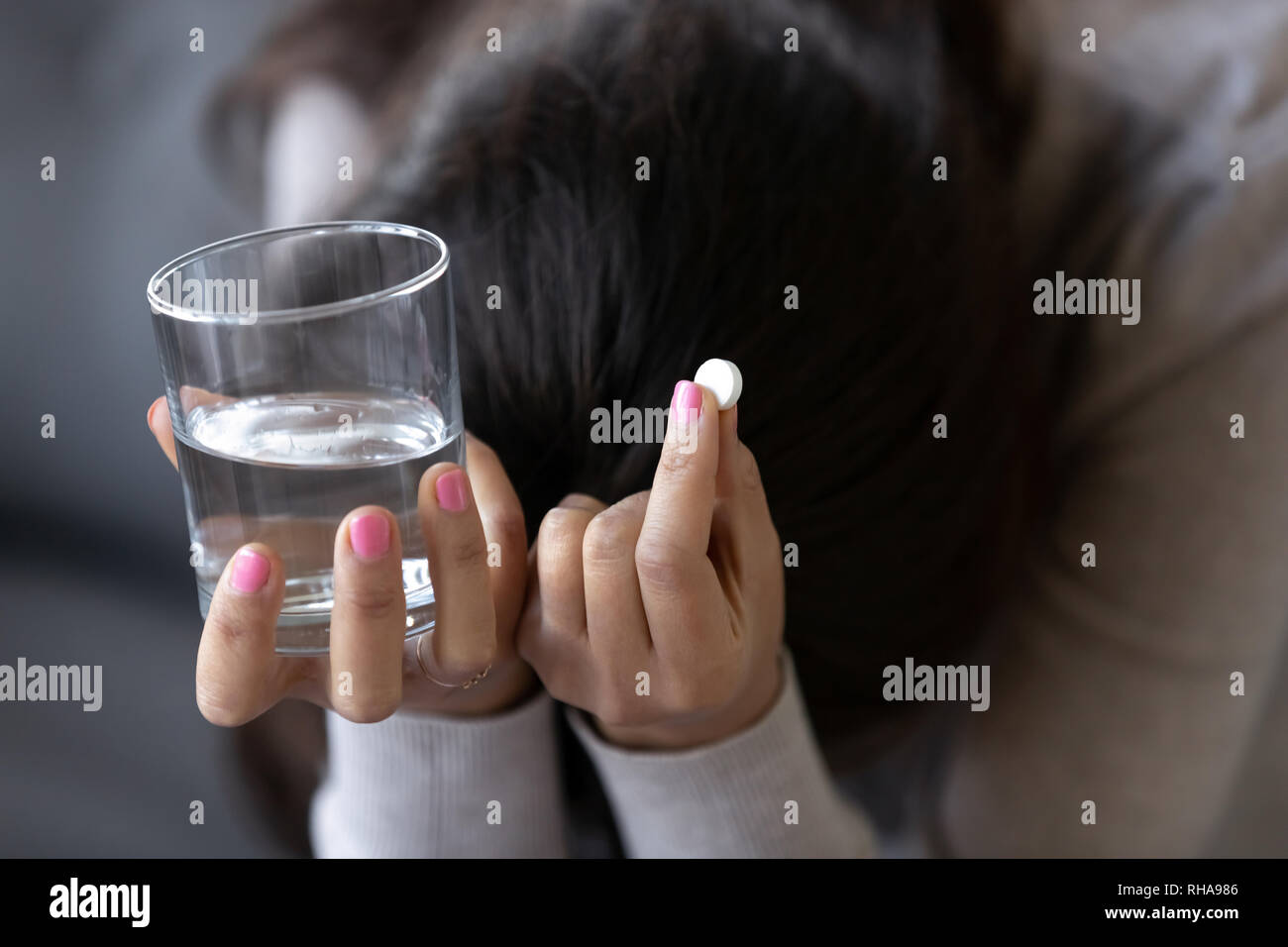 Sad depressed woman holding pill and glass of water Stock Photo