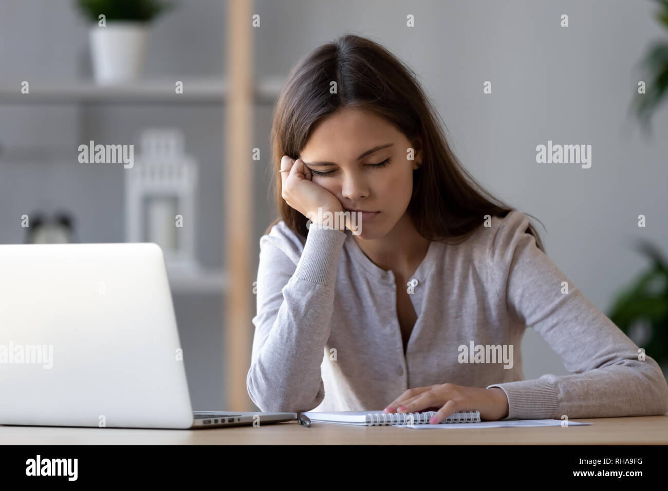 Bored funny woman resting on hand sleeping at workplace Stock Photo