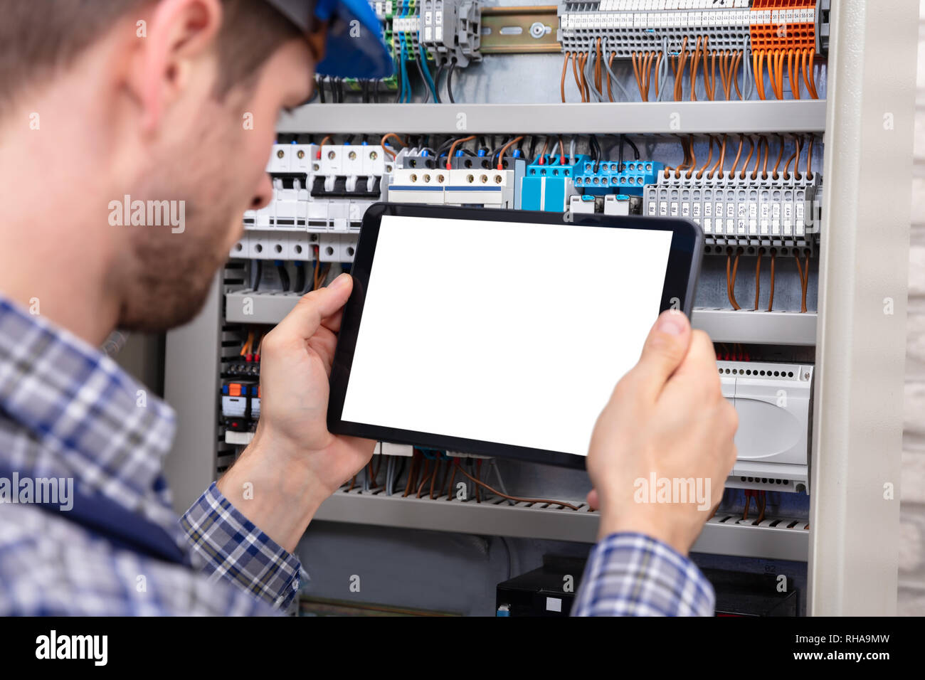 Technician Holding Digital Tablet With Blank Screen In Front Of Fuse Box Stock Photo