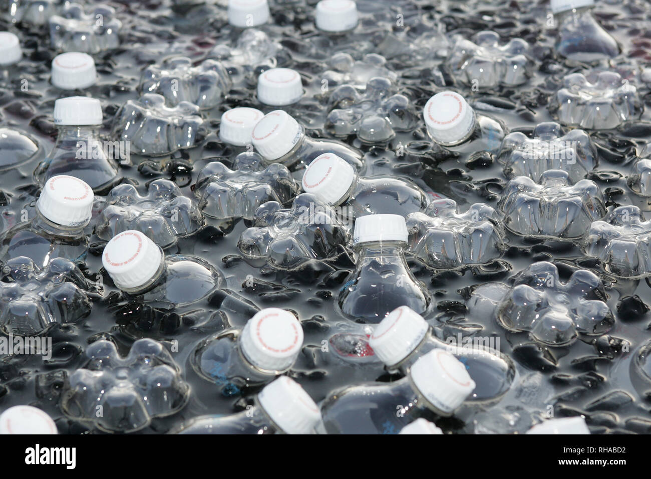 Bottles of water sit in a cooler of ice water on a hot day Stock Photo