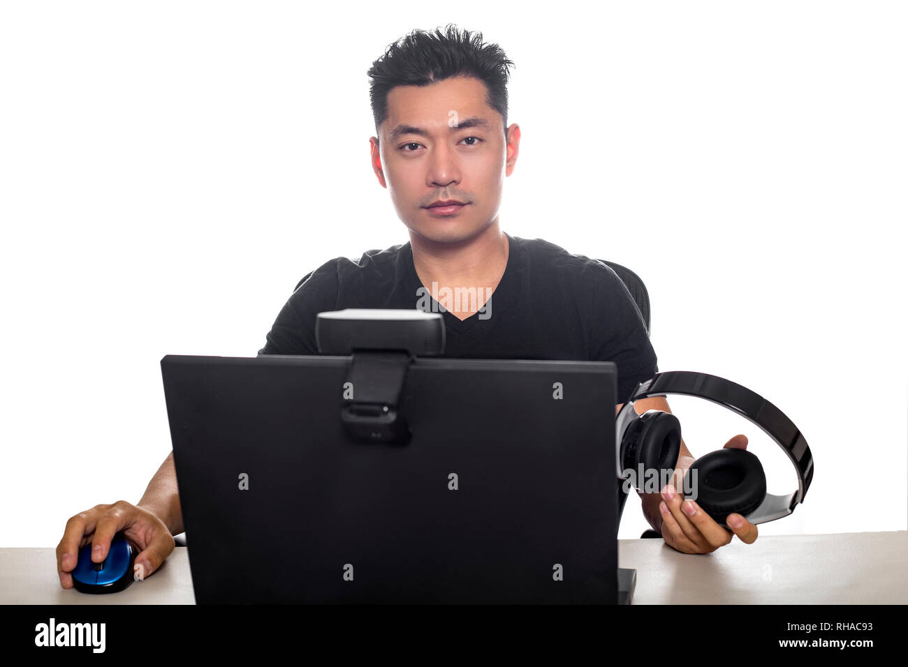 Asian male wearing headphones playing a video game and streaming online  with a webcam on a laptop pc. The image depicts entertainment industry and  el Stock Photo - Alamy