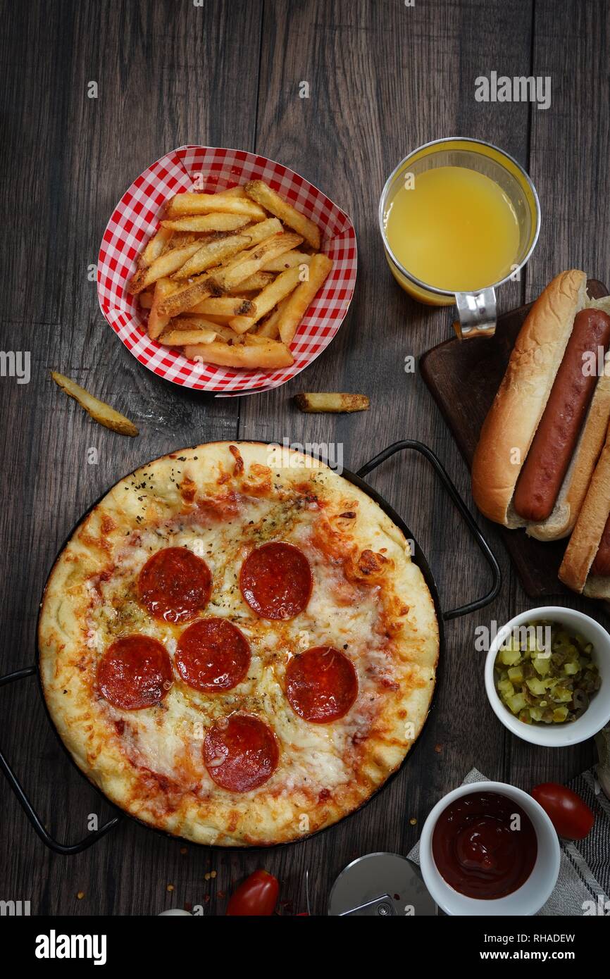 Party game day food Homemade Pizza hot dogs fries juice and dips - Super bowl food concept overhead view Stock Photo
