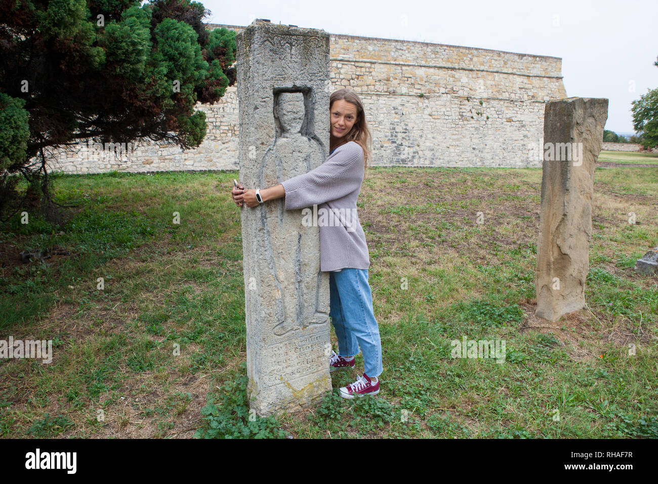 Young tourist girl embracing ancient stone sculpture Stock Photo