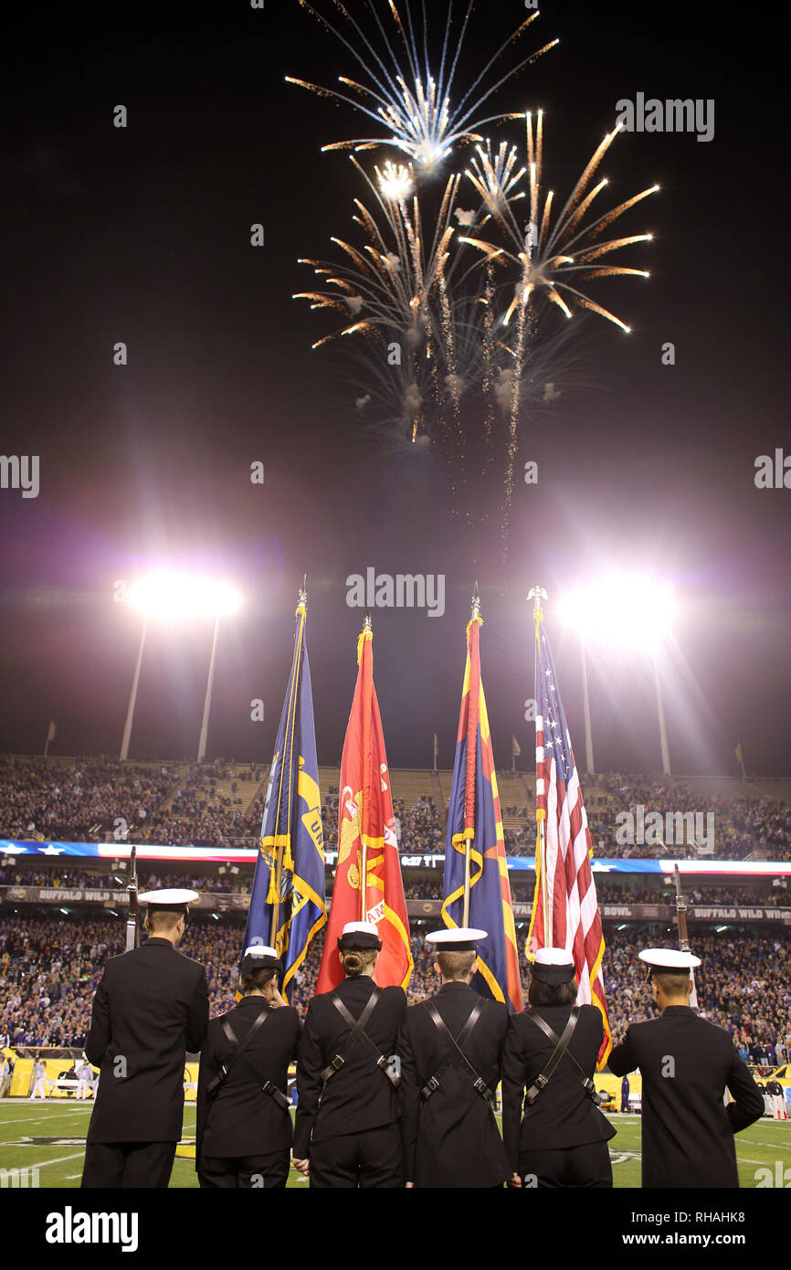 The color guard stands at attention with flags raised as the National Anthem is sung and fireworks explode in the sky. Stock Photo