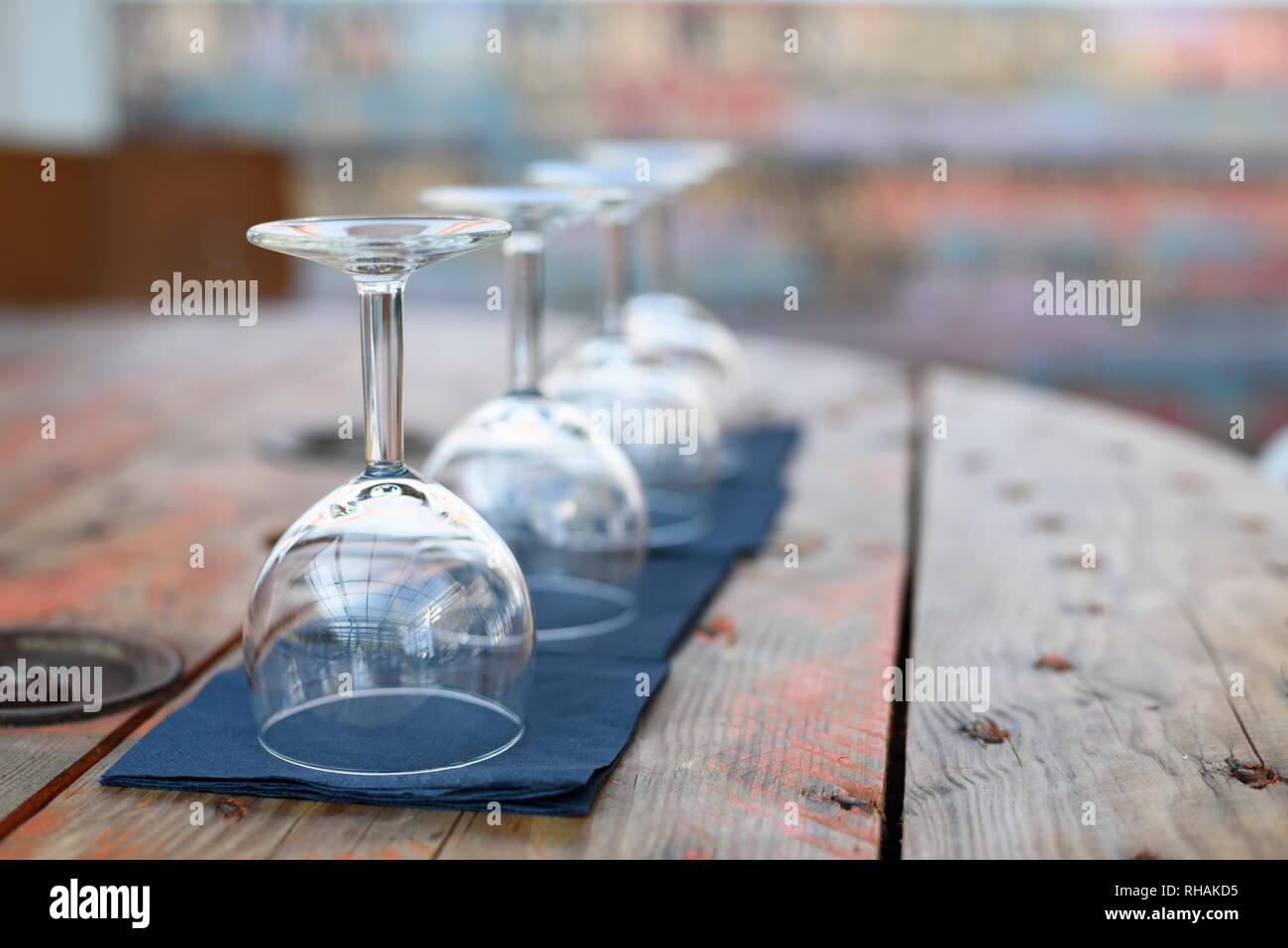 Empty wine glasses on rustic wooden table in retro restaurant interior. Stock Photo