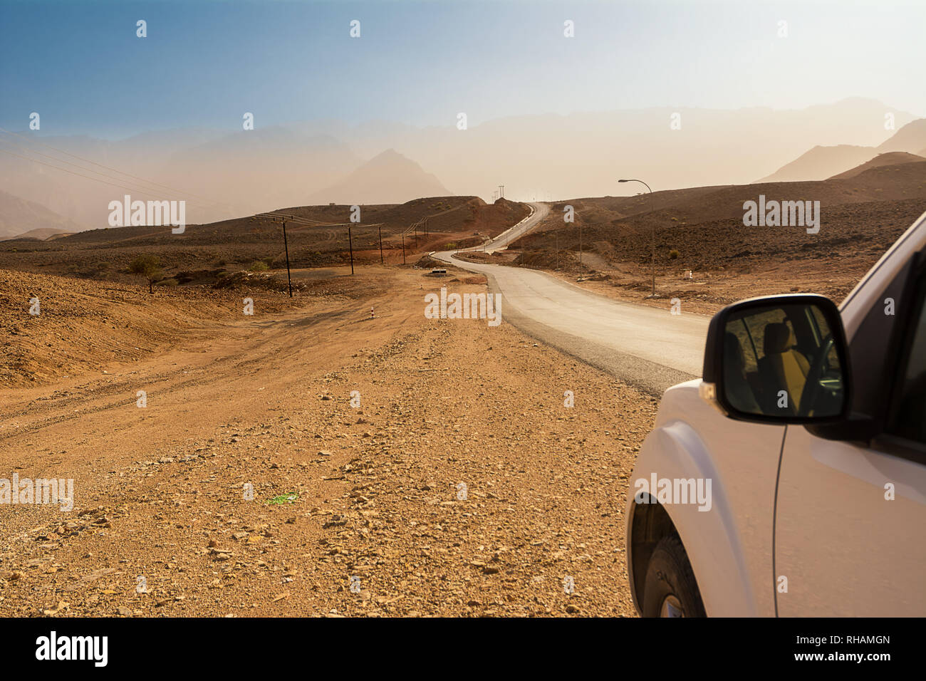 Asphalt road in the rocky desert and detail of a 4x4 car Stock Photo
