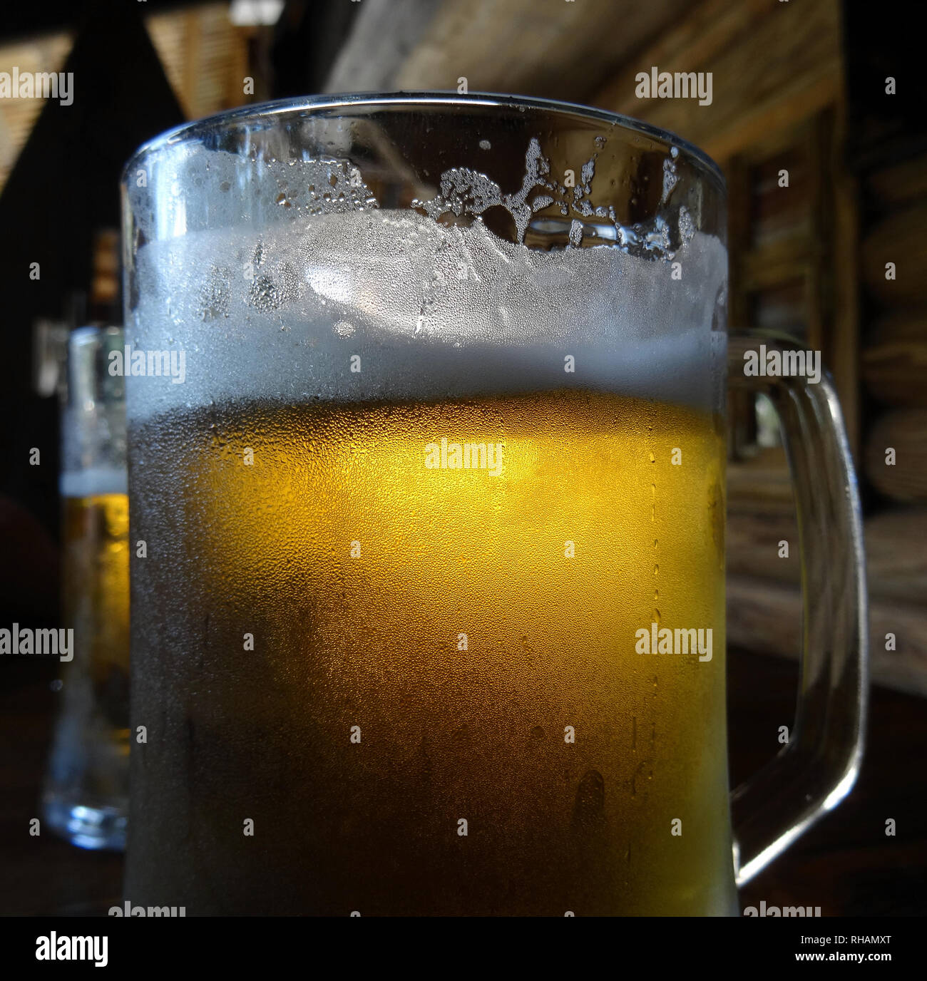 Two beer pints in cold glasses with foam on the wooden table at country restaurant Stock Photo
