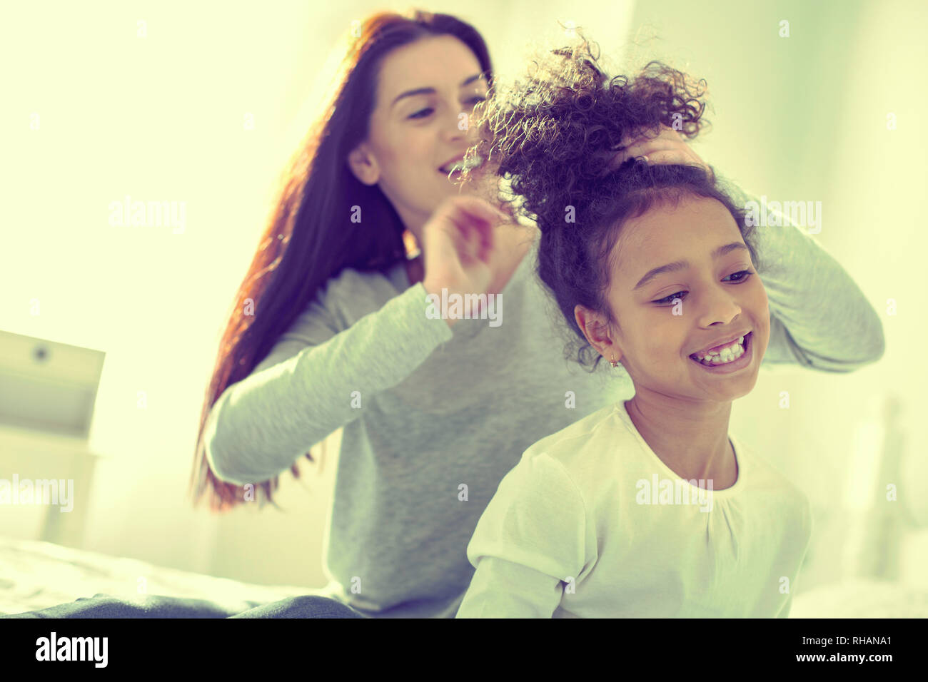 Caring Responsible Mom Brushing Hair Of Her Mulatto Daughter Stock