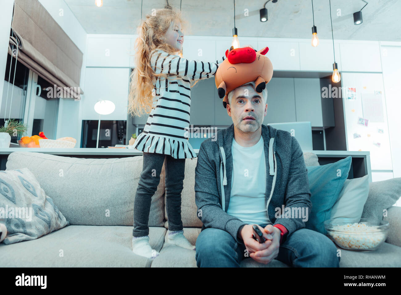 Cute long-haired girl in a dress playing with her father Stock Photo