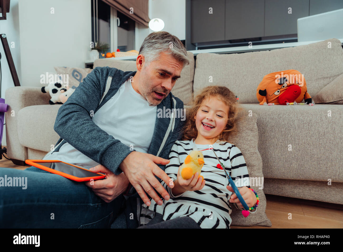 Handsome grey-haired tall father with a red watch on his hand looking shocked Stock Photo