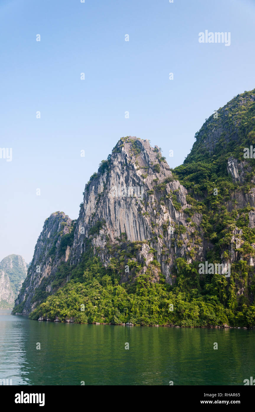 A limestone karst covered in vegetation in early morning light, Halong Bay, Vietnam Stock Photo