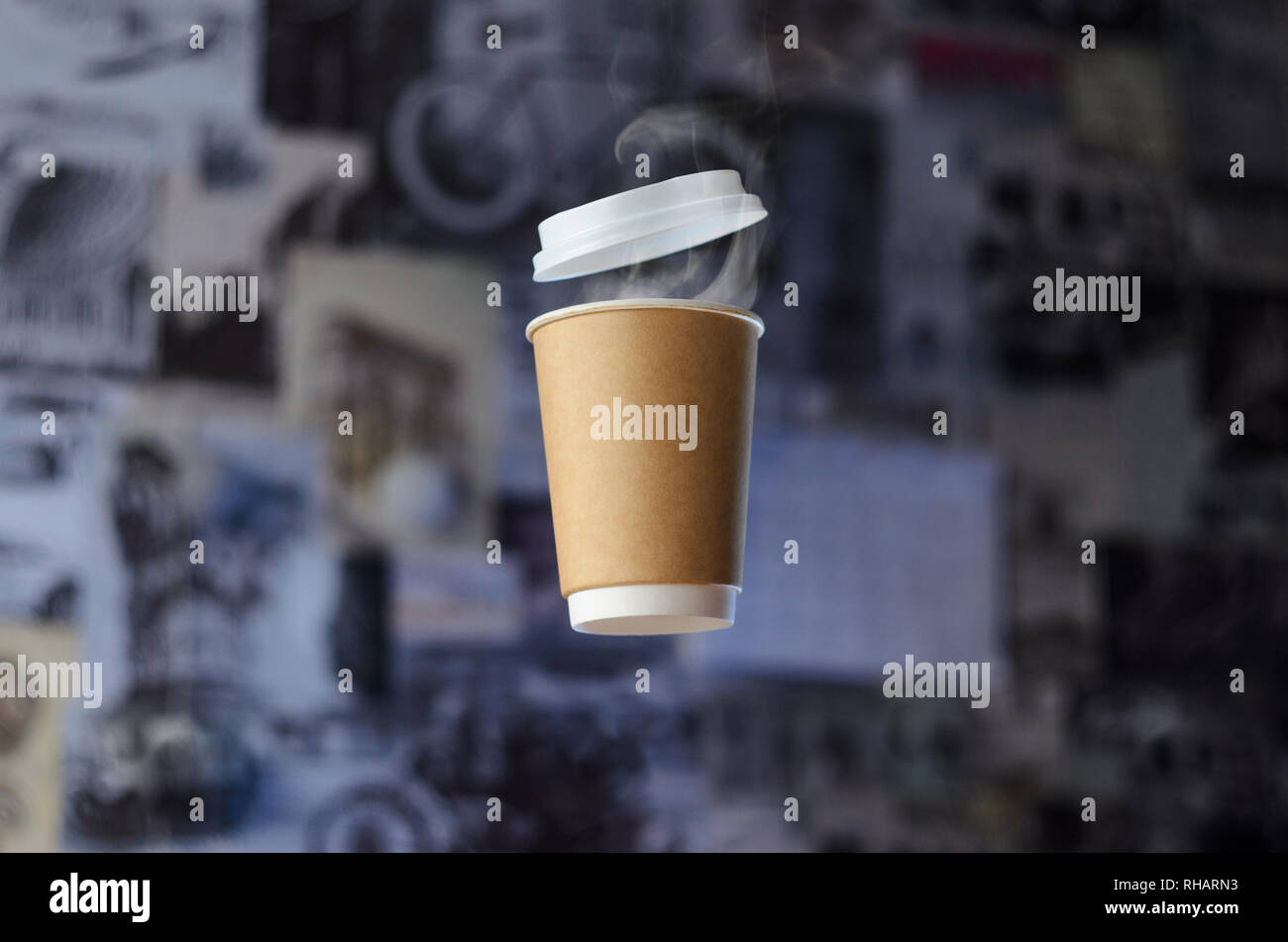 Paper cup with evaporation from a hot coffee with plastic cap levitates in the air on a gray background. Empty Place for Logo Placement Stock Photo