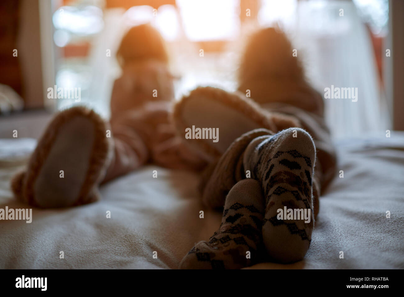 Feet in Christmas socks on the background of the window on a winter sunny day. Warm cozy atmosphere Stock Photo