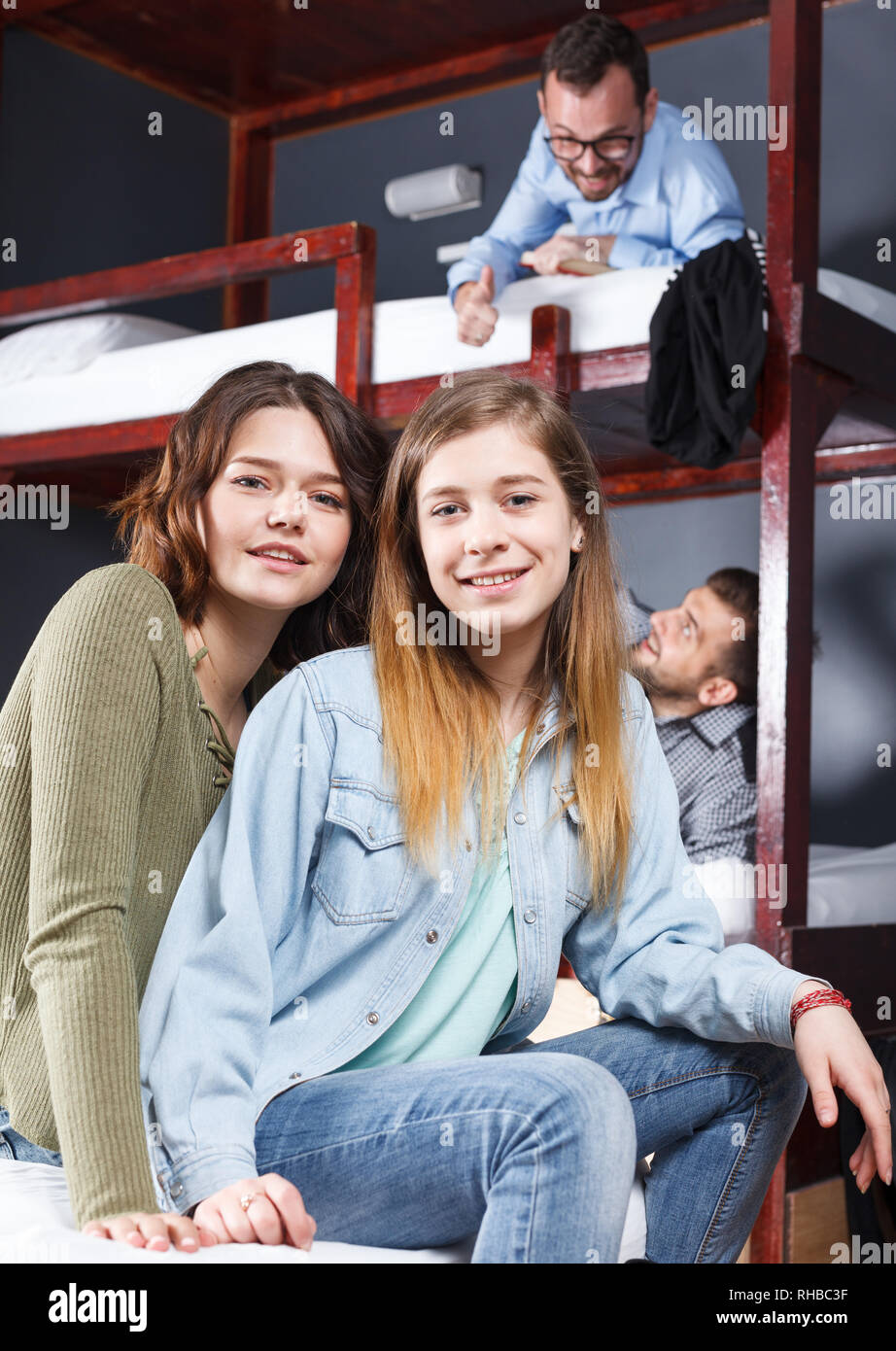 Portrait of two happy girls having fun while resting in bedroom of modern hostel Stock Photo