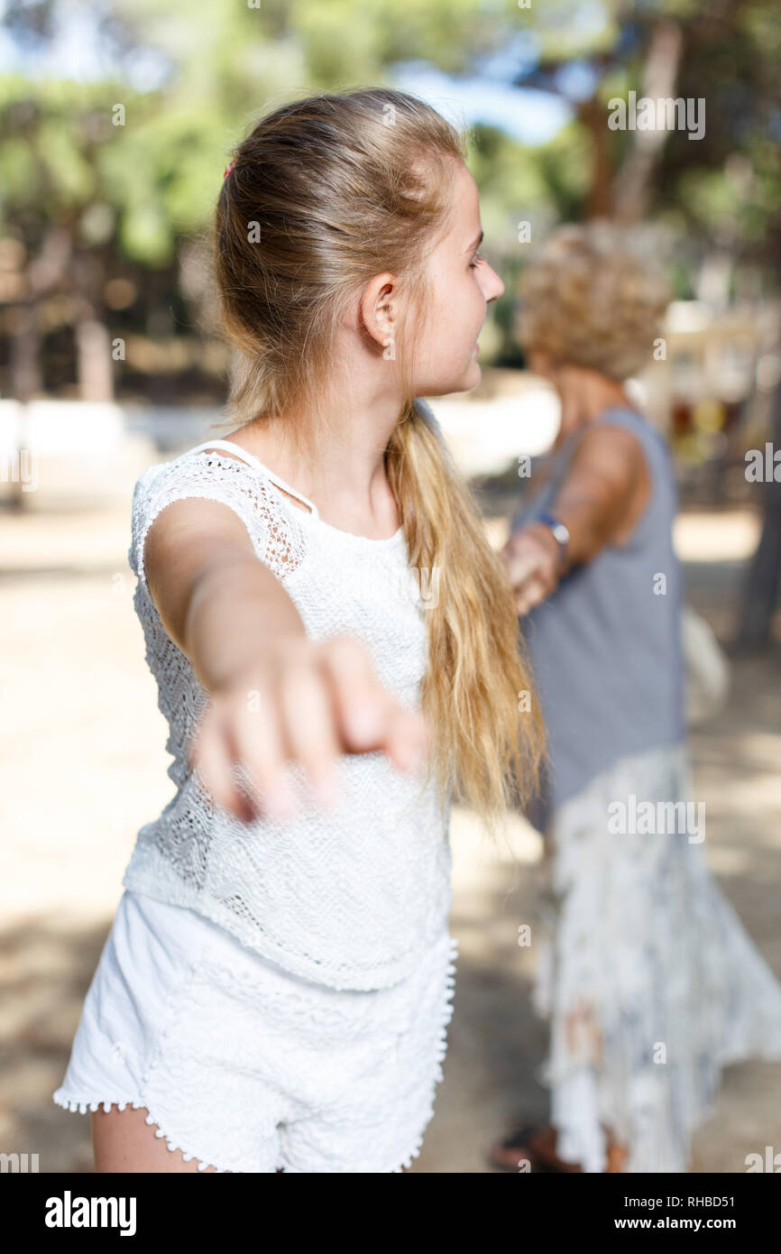 Portrait of teenage girl pulling hand and hold grandmother on hand in