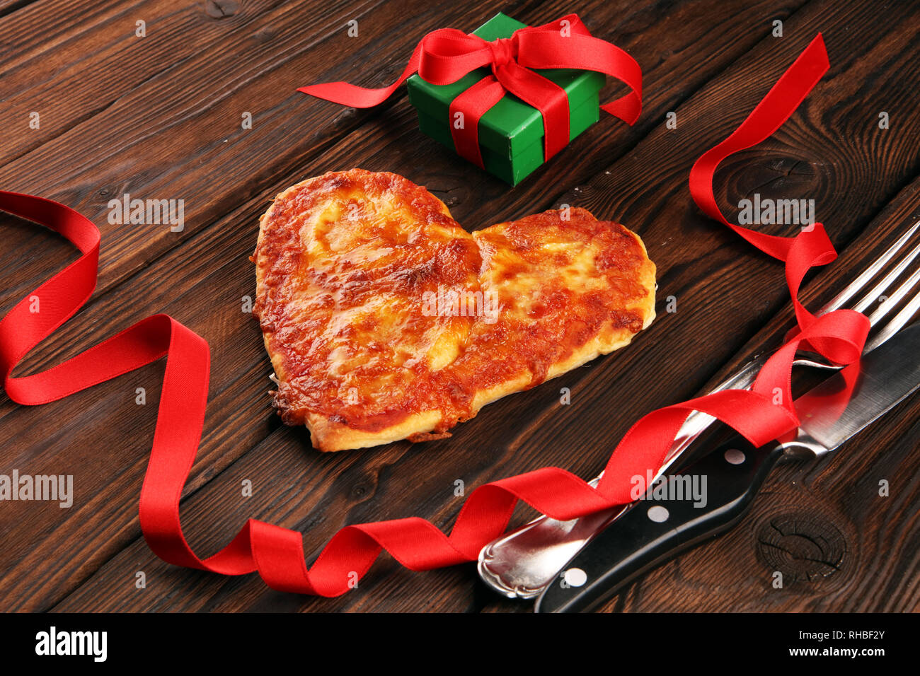 Valentines day pizza in heart shape on dark rustic wooden background ...