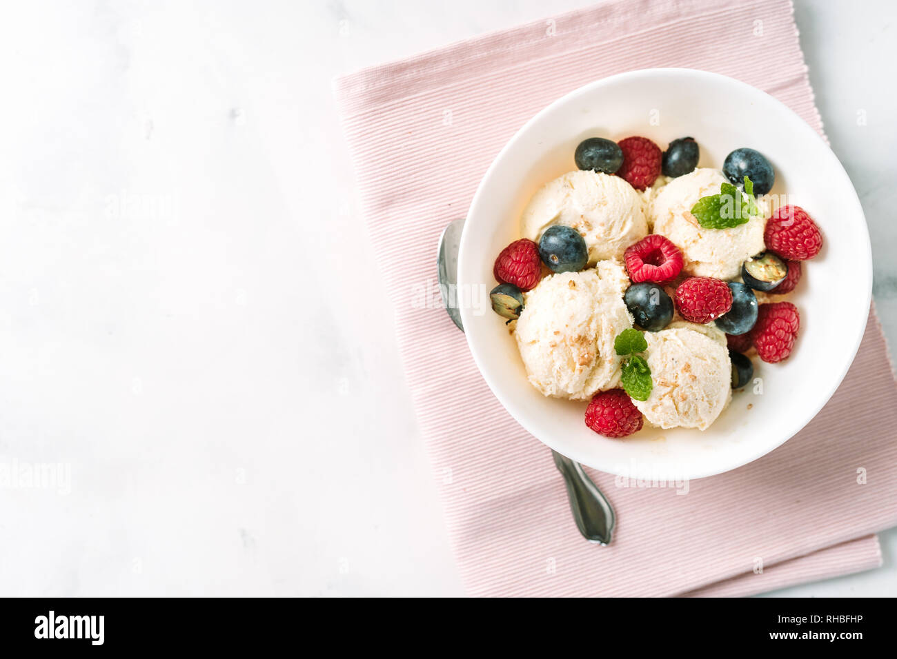 Top view of vanilla ice cream with berries in a bowl on pink serviette Stock Photo
