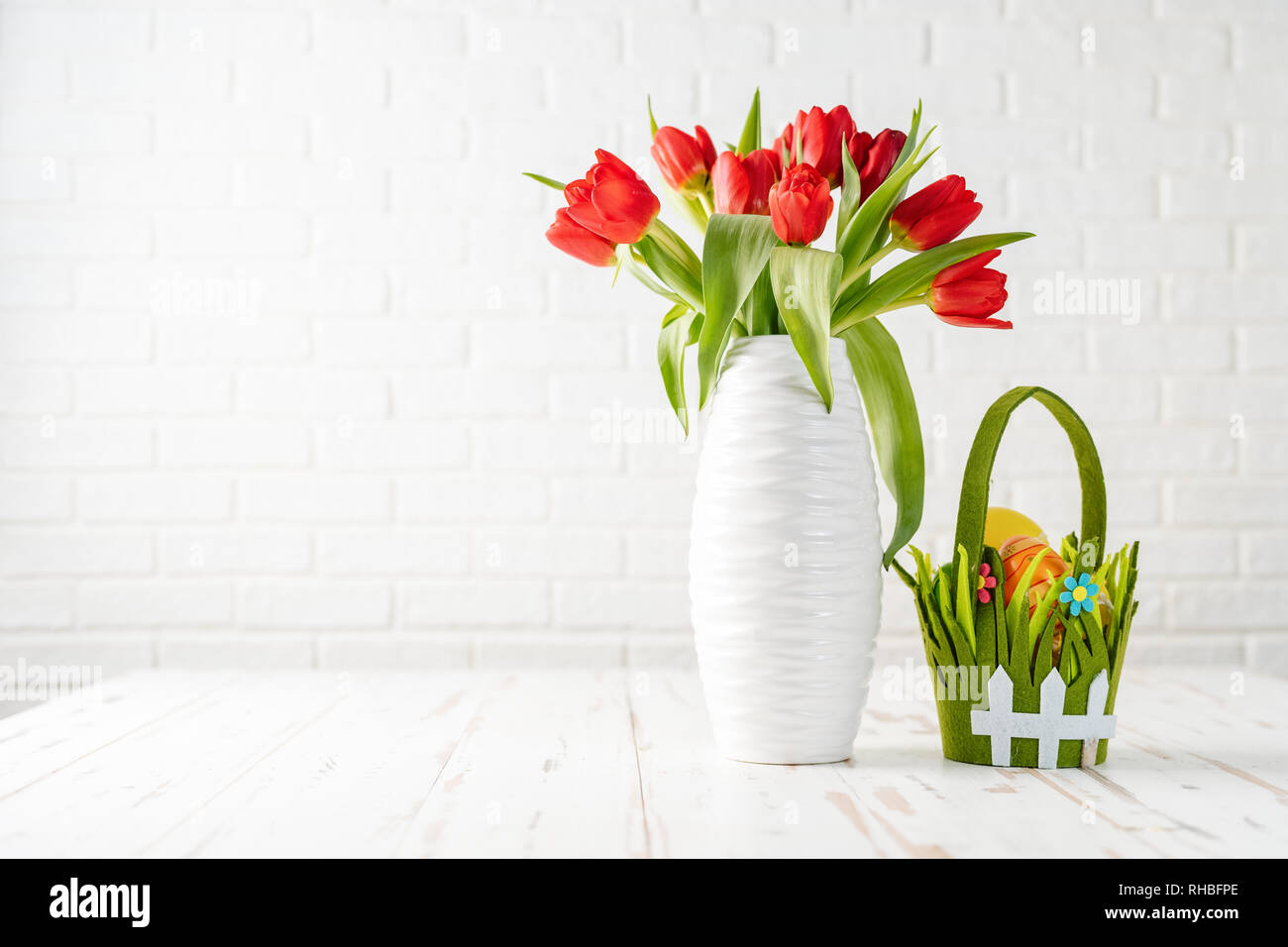 Easter composition with tulips in white vase and eggs in a basket on ...