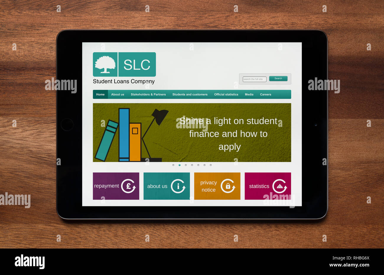 The website of Student Loans Company (SLC) is seen on an iPad tablet, which is resting on a wooden table (Editorial use only). Stock Photo