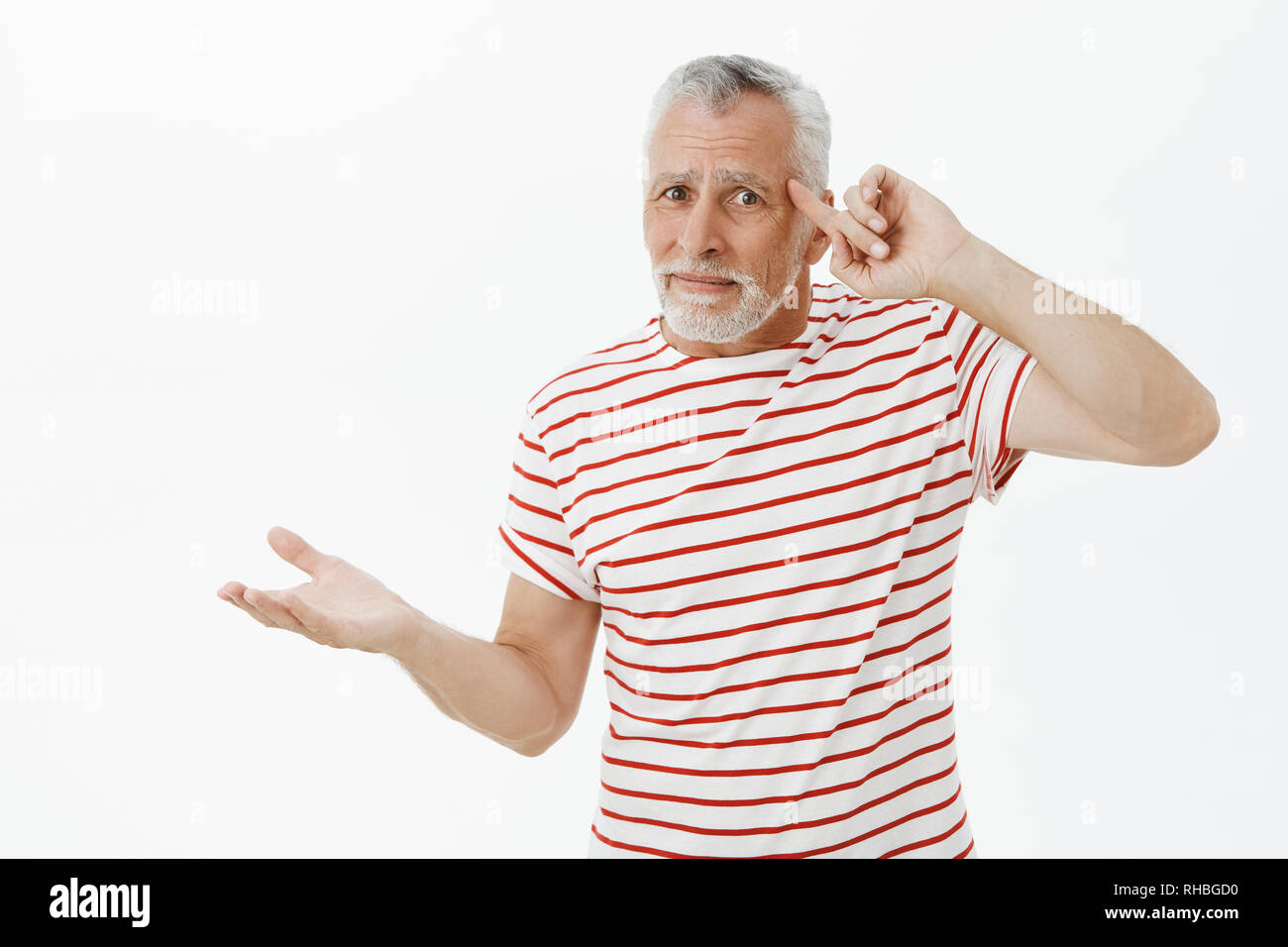 Old man things teenagers lost mind, insane. Confused and displeased senior  bearded male in striped t-shirt rolling finger on temple from Stock Photo -  Alamy