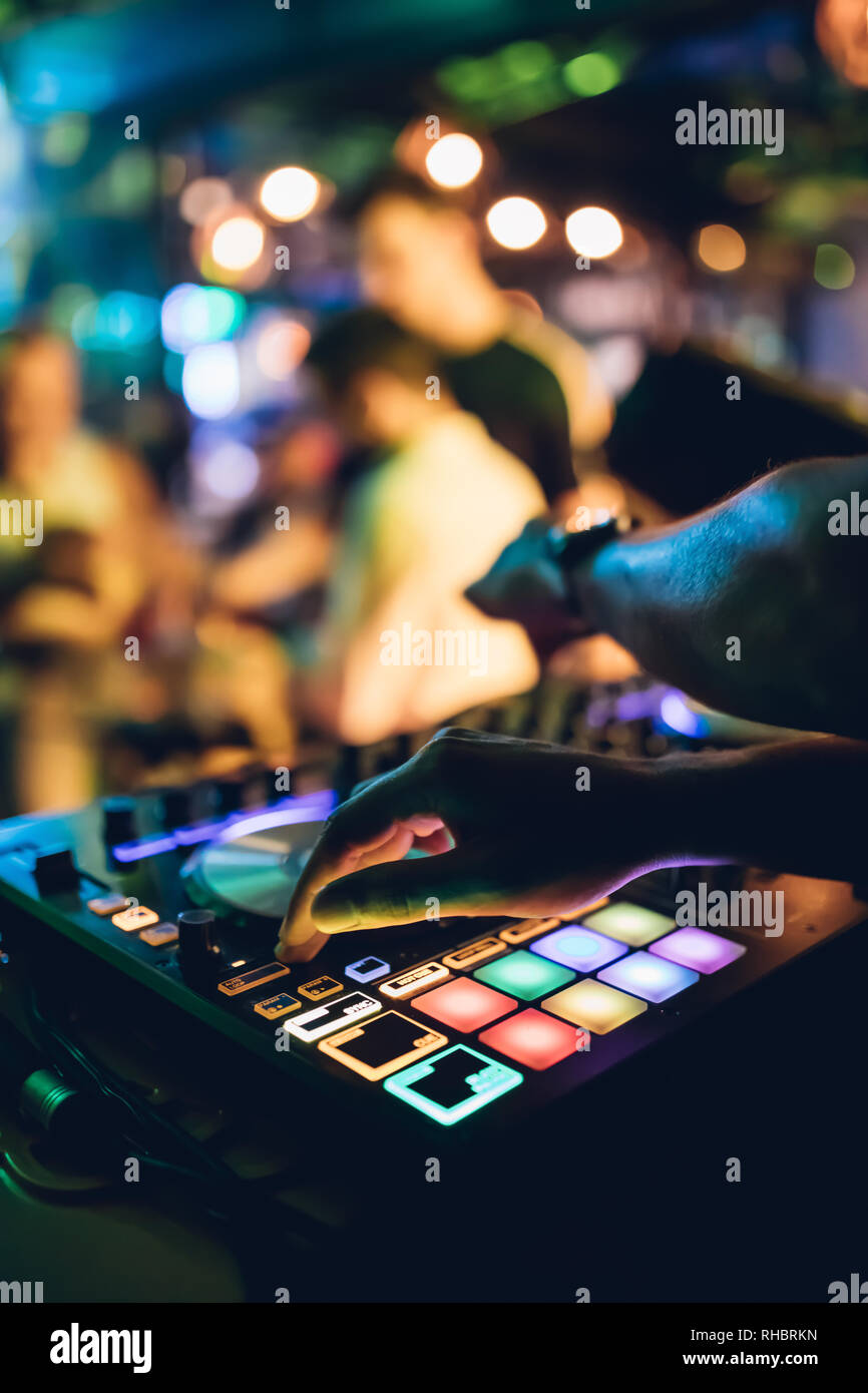 DJ plays live set and mixing music on turntable console at stage in the