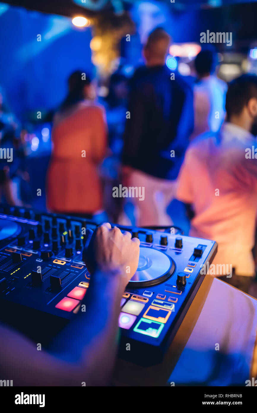 DJ plays live set and mixing music on turntable console at stage in the