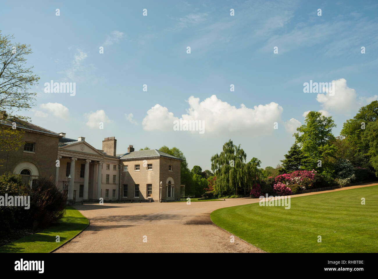 The grounds of Kenwood House with lawns, distant azaleas, on a beautiful sunny spring day, with blue skies and fluffy white clouds.lawn Stock Photo