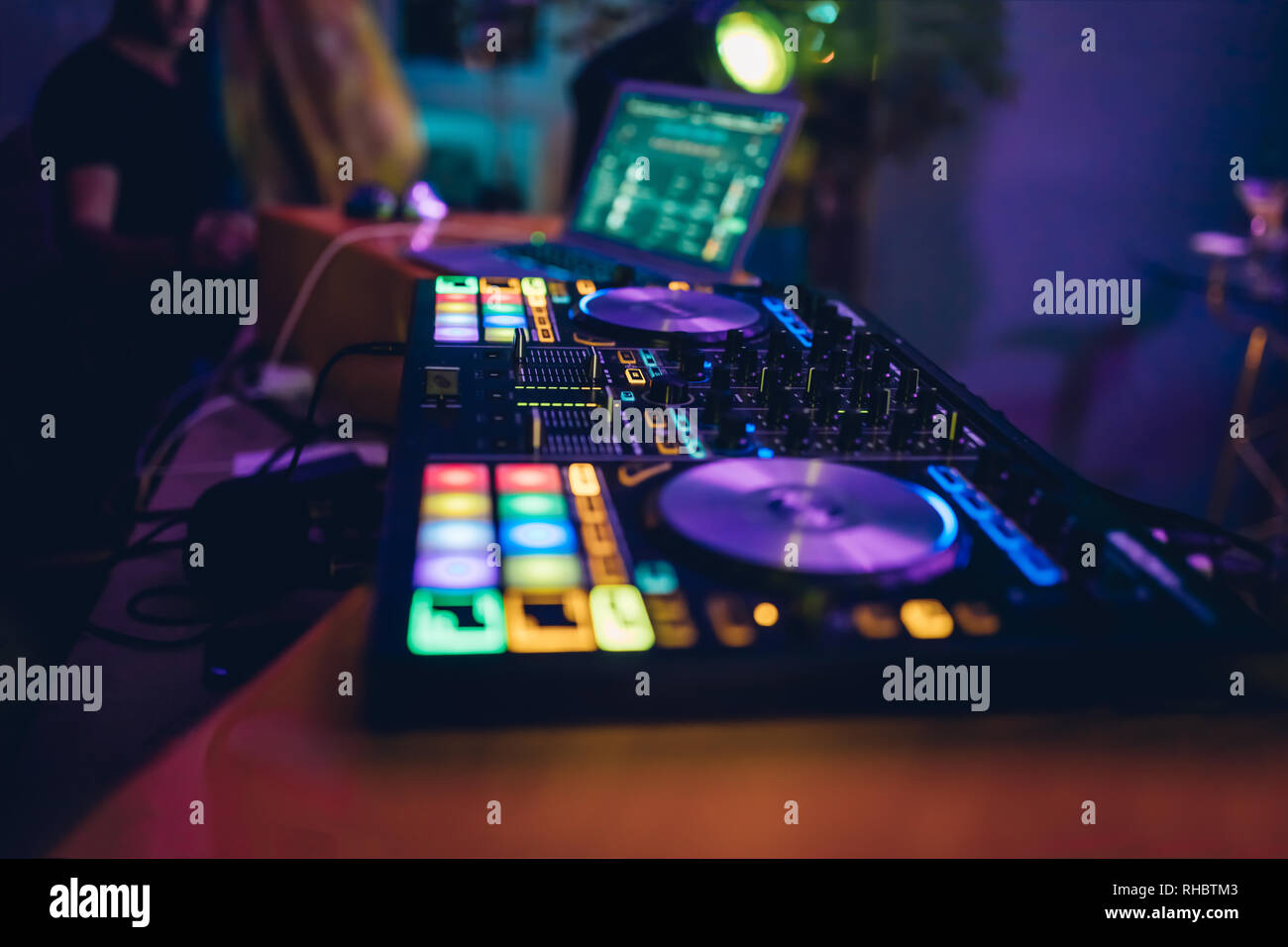 DJ plays live set and mixing music on turntable console at stage in the night club. Disc Jokey Hands on a sound mixer station at club party. DJ mixer Stock Photo
