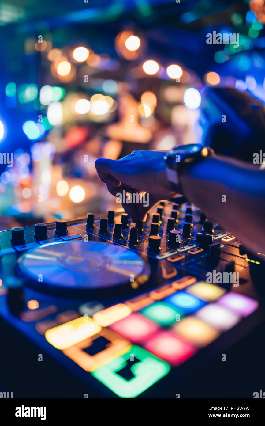 DJ plays live set and mixing music on turntable console at stage in the