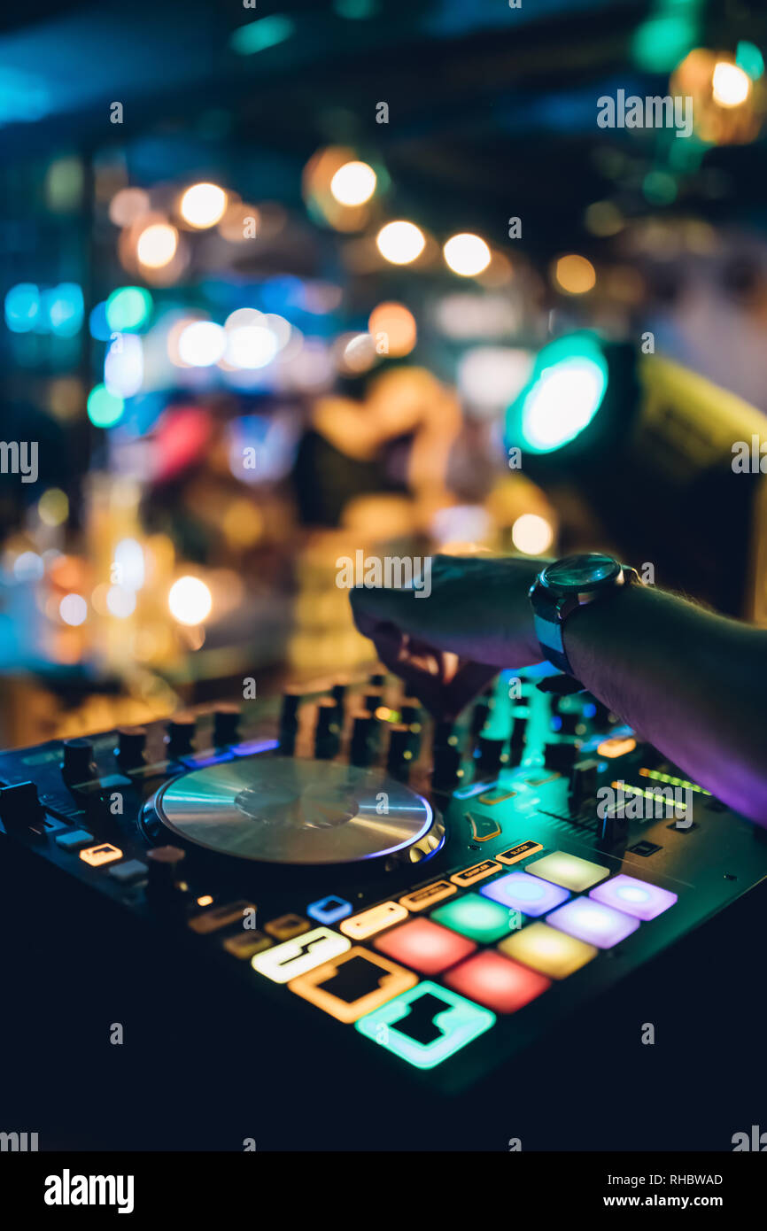 DJ plays live set and mixing music on turntable console at stage in the