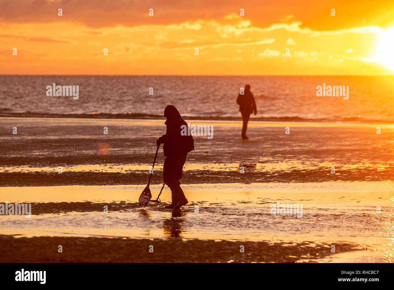 Metal detectorists with a shovel and a spade scour Blackpool beach for