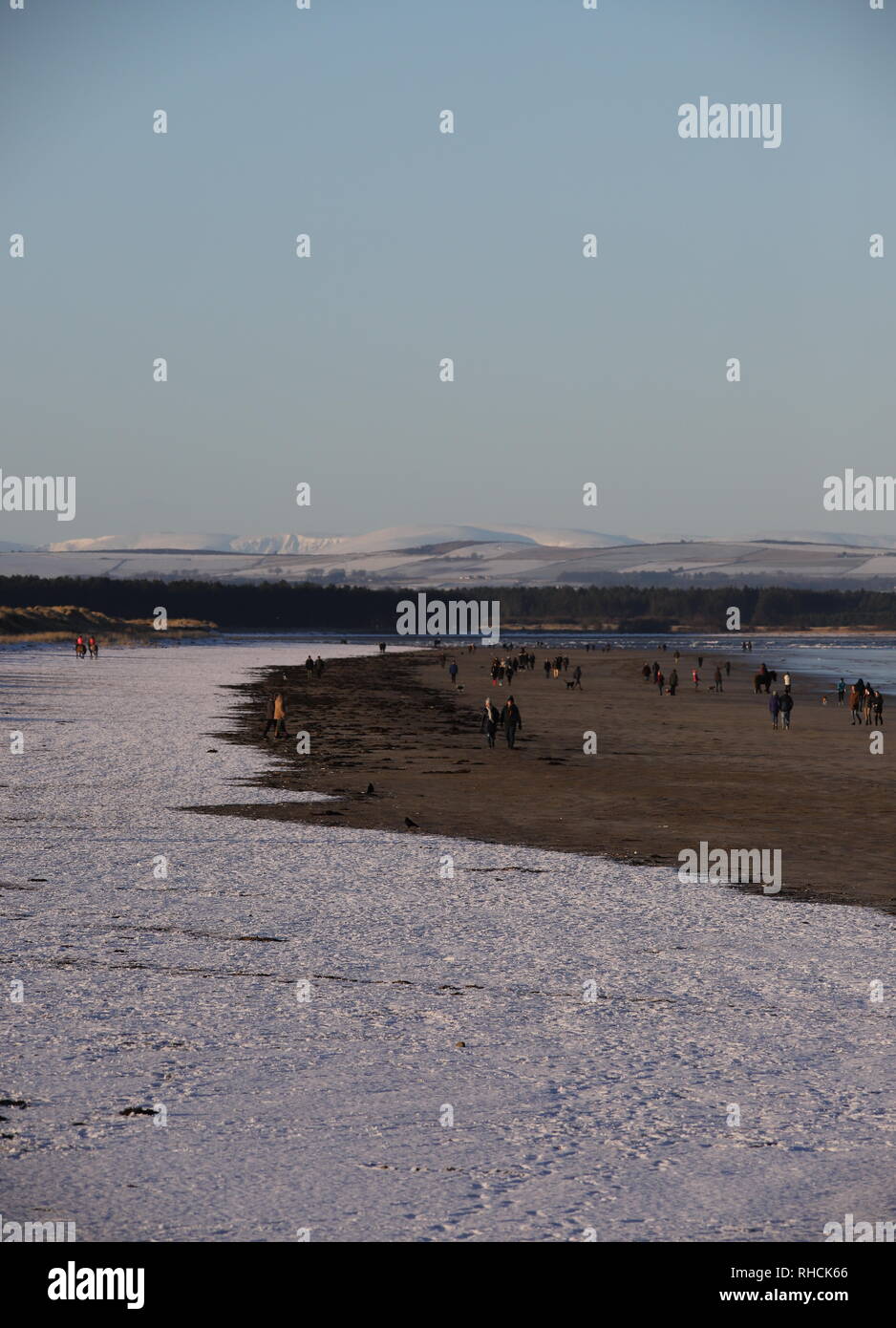 St Andrews, UK. 2nd February 2019. People walking on West Sands beach St Andrews after overnight snow with distant snow covered peaks in the Angus Glens.  © Stephen Finn/Alamy Live News Stock Photo