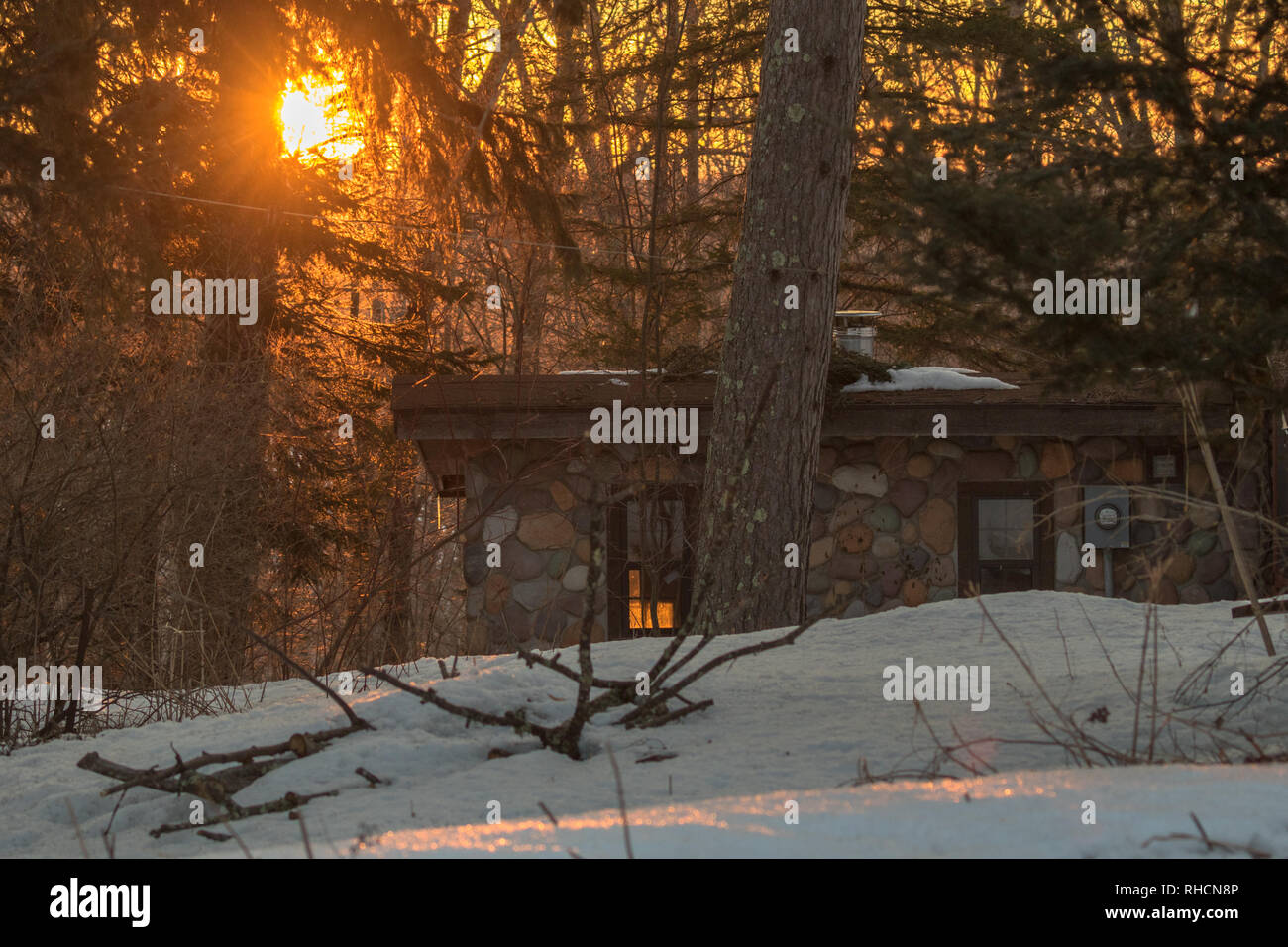 The rising sun illuminates a stone cabin in northern Wisconsin Stock