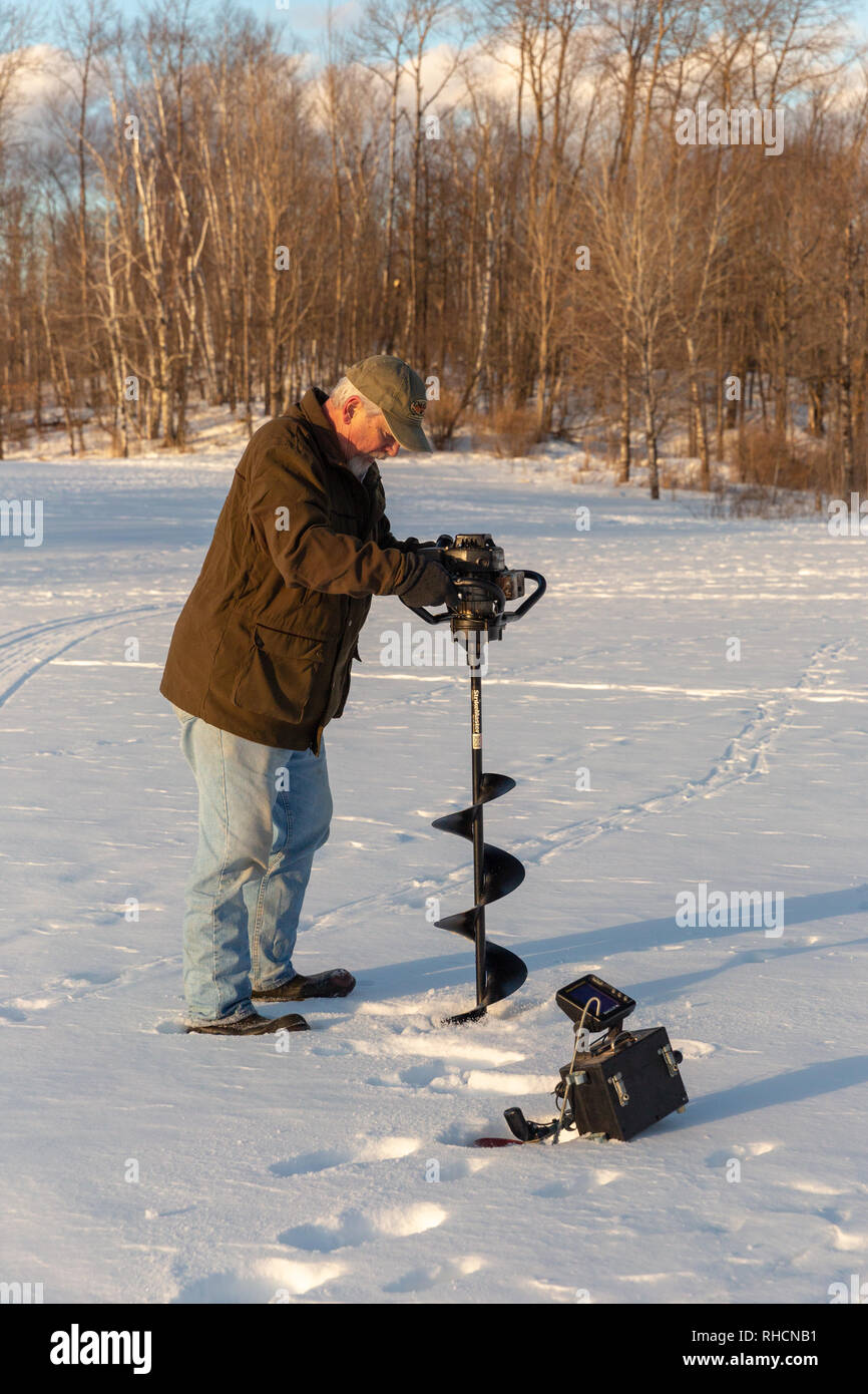Fisherman using an ice auger to drill a hole in the ice Stock Photo Alamy